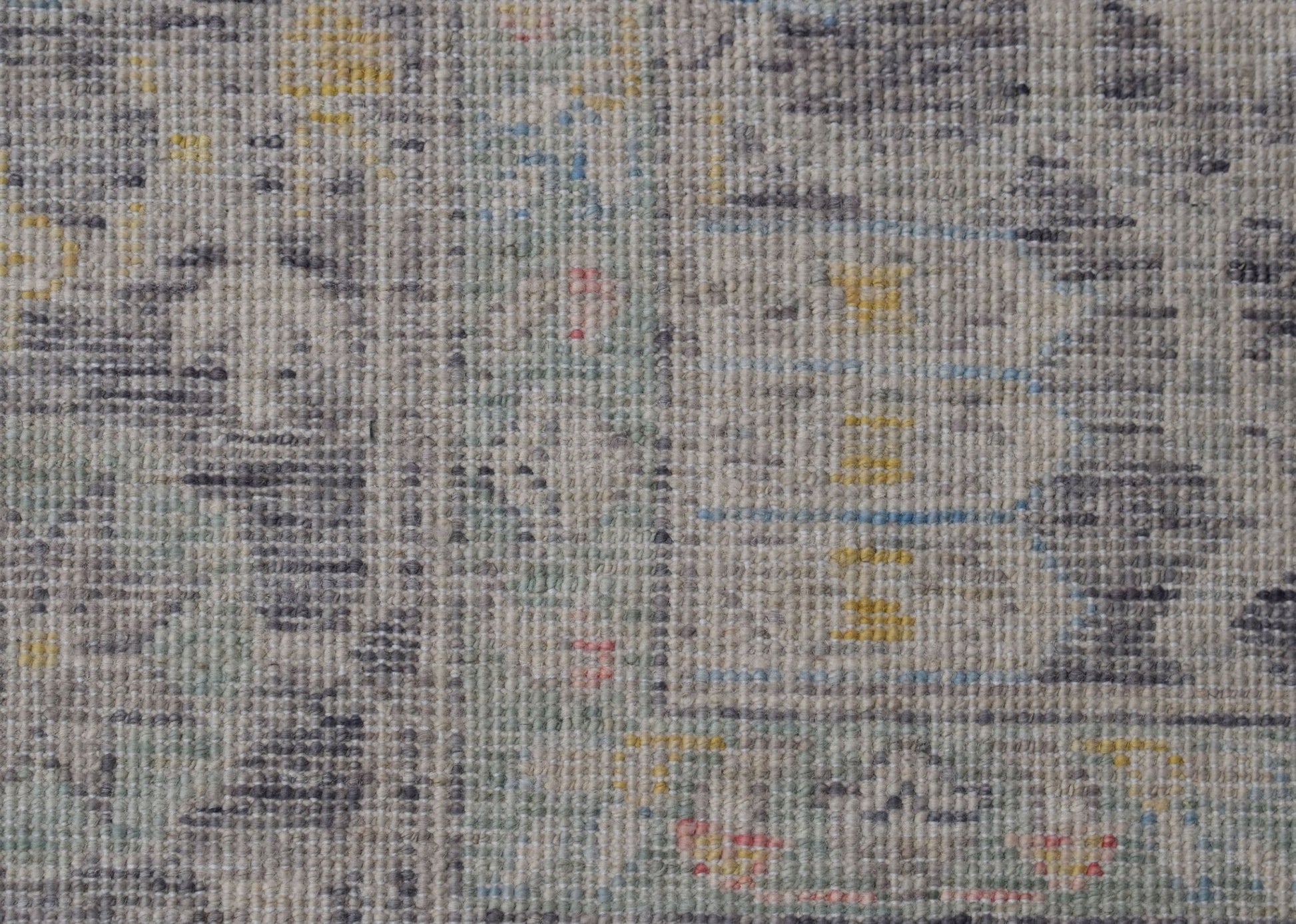 A handwoven transitional Oushak rug featuring a distressed pattern in grey, yellow, and blue tones.