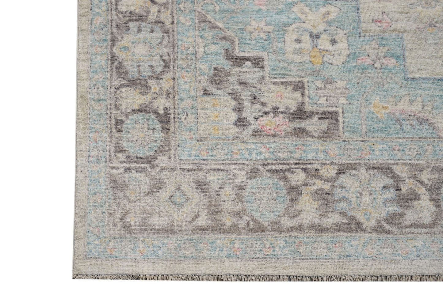 A handwoven transitional Oushak rug featuring a floral pattern in blue, grey, and cream tones.