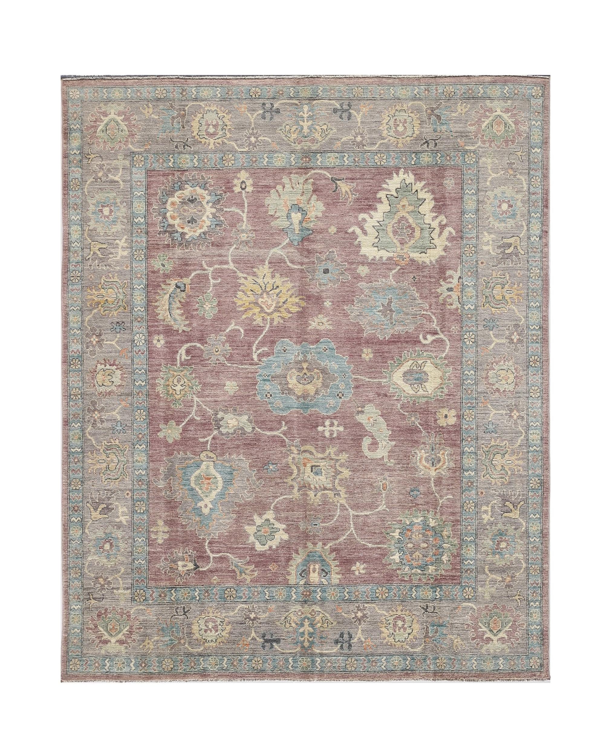 A handwoven transitional Oushak rug featuring a floral pattern in muted tones on a mauve field.