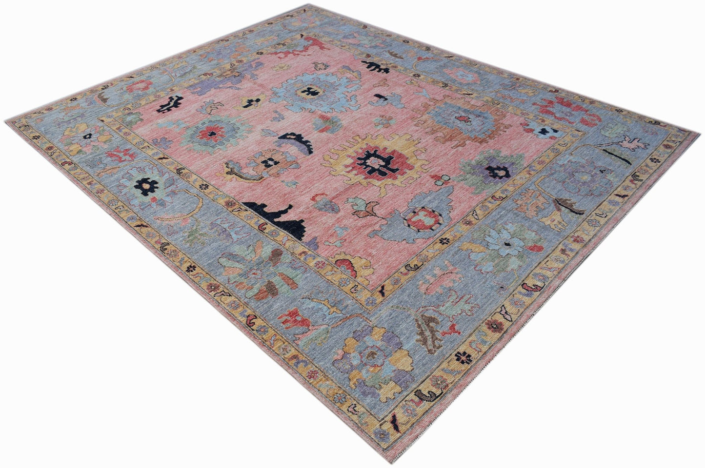 A handwoven transitional Oushak rug featuring a floral pattern in soft pink and blue tones.