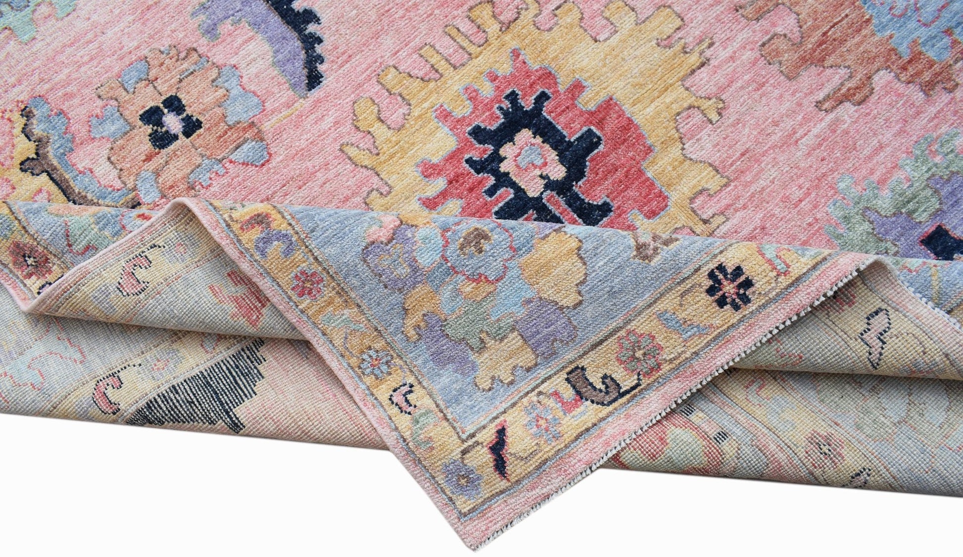 A handwoven transitional Oushak rug with a floral pattern in pink, blue, and yellow tones.