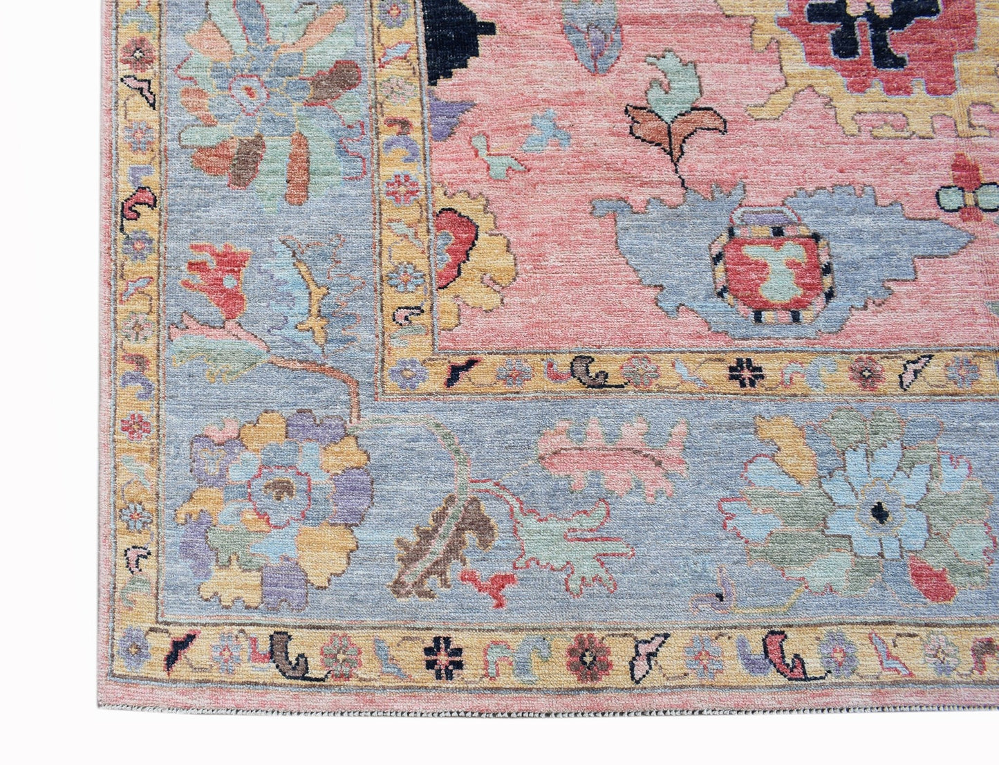 A handwoven transitional Oushak rug featuring a floral pattern in soft pink and blue tones.