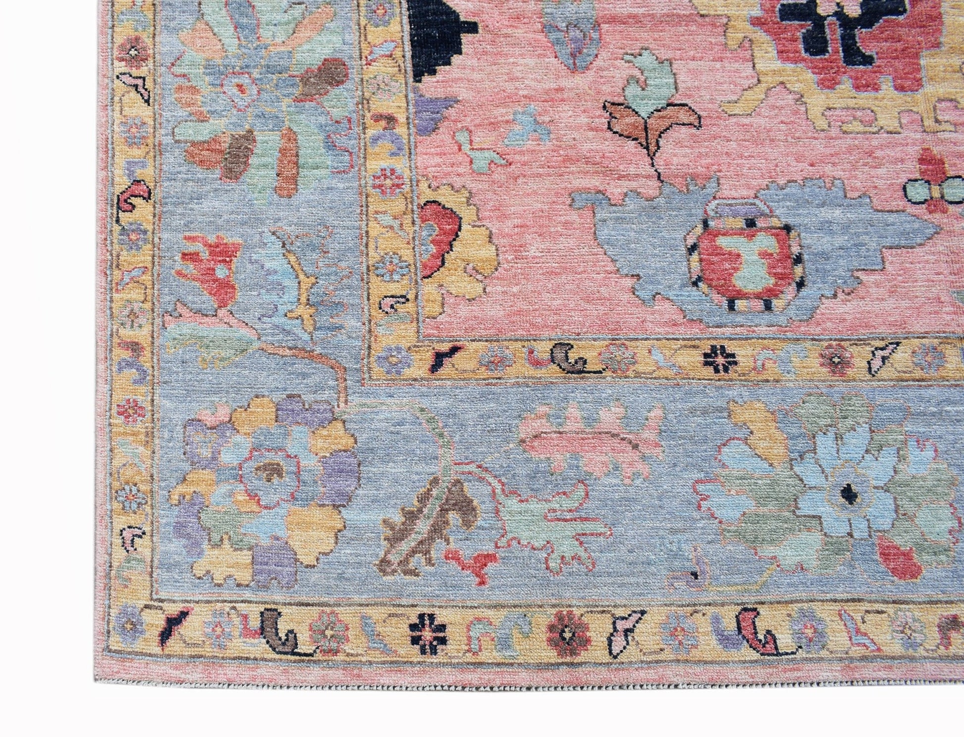 A handwoven transitional Oushak rug featuring a floral pattern in soft pink and blue tones.