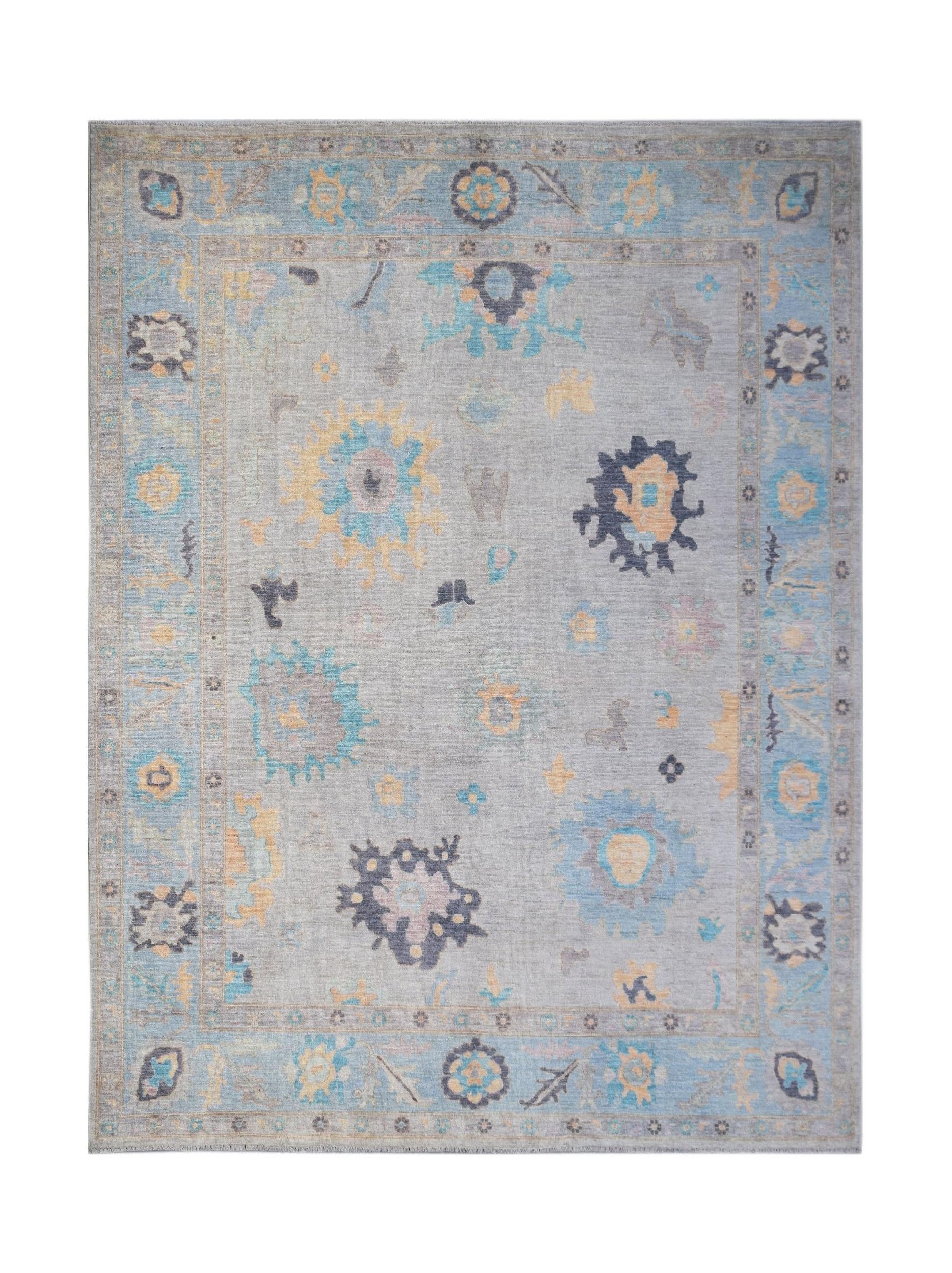 A transitional Oushak rug featuring a light grey field with scattered floral motifs in blue and gold.