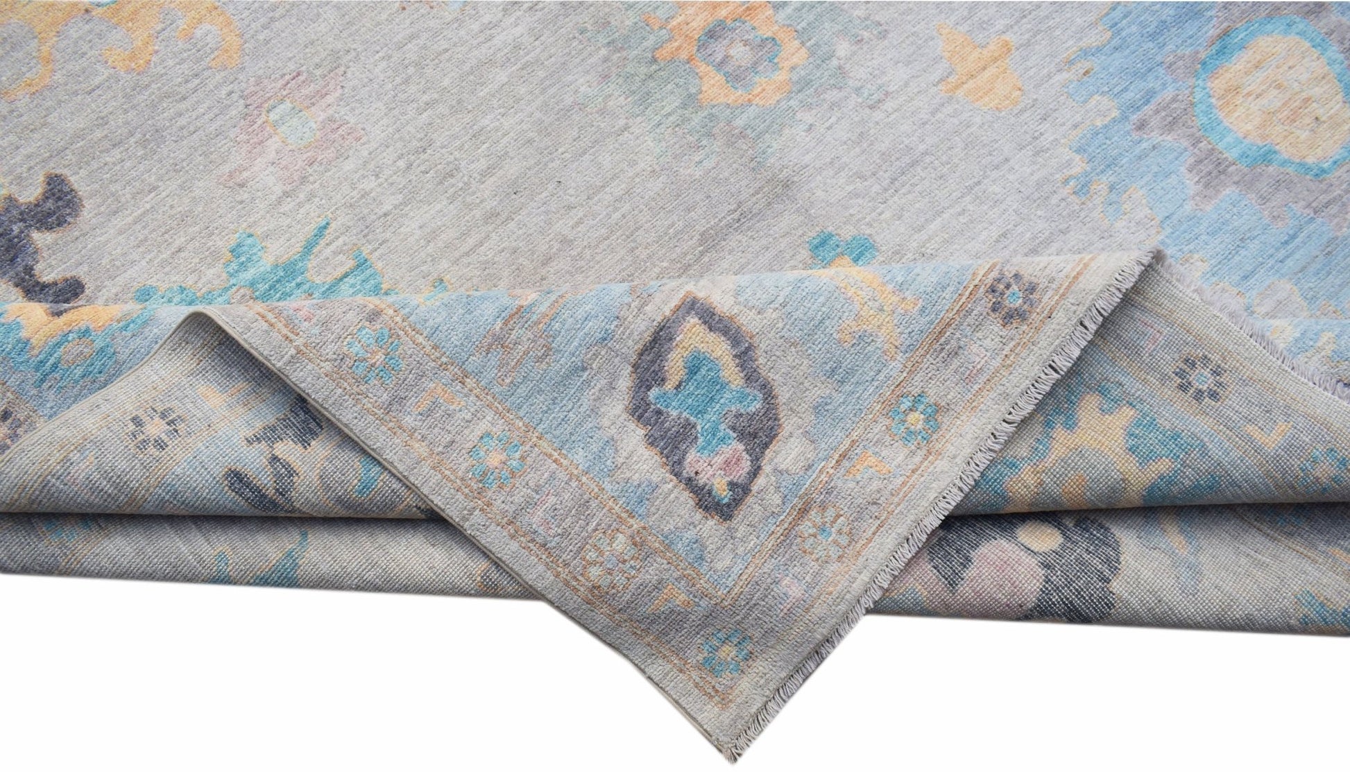 A handwoven transitional Oushak rug featuring a floral pattern in blue, grey, and soft yellow tones.