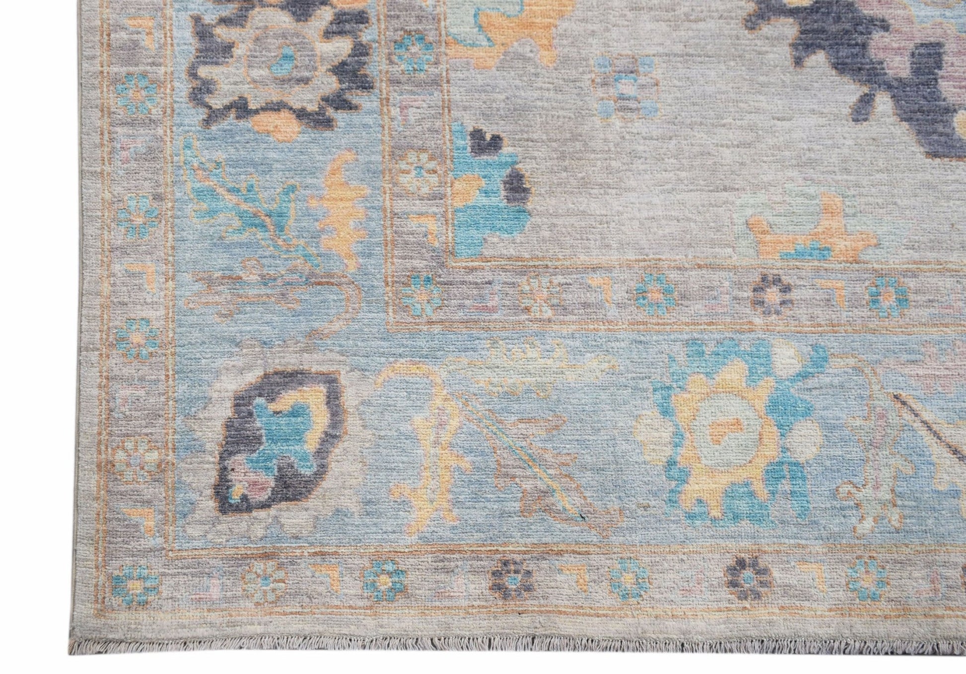A handwoven transitional Oushak rug featuring a floral pattern in blue, grey, and soft yellow.