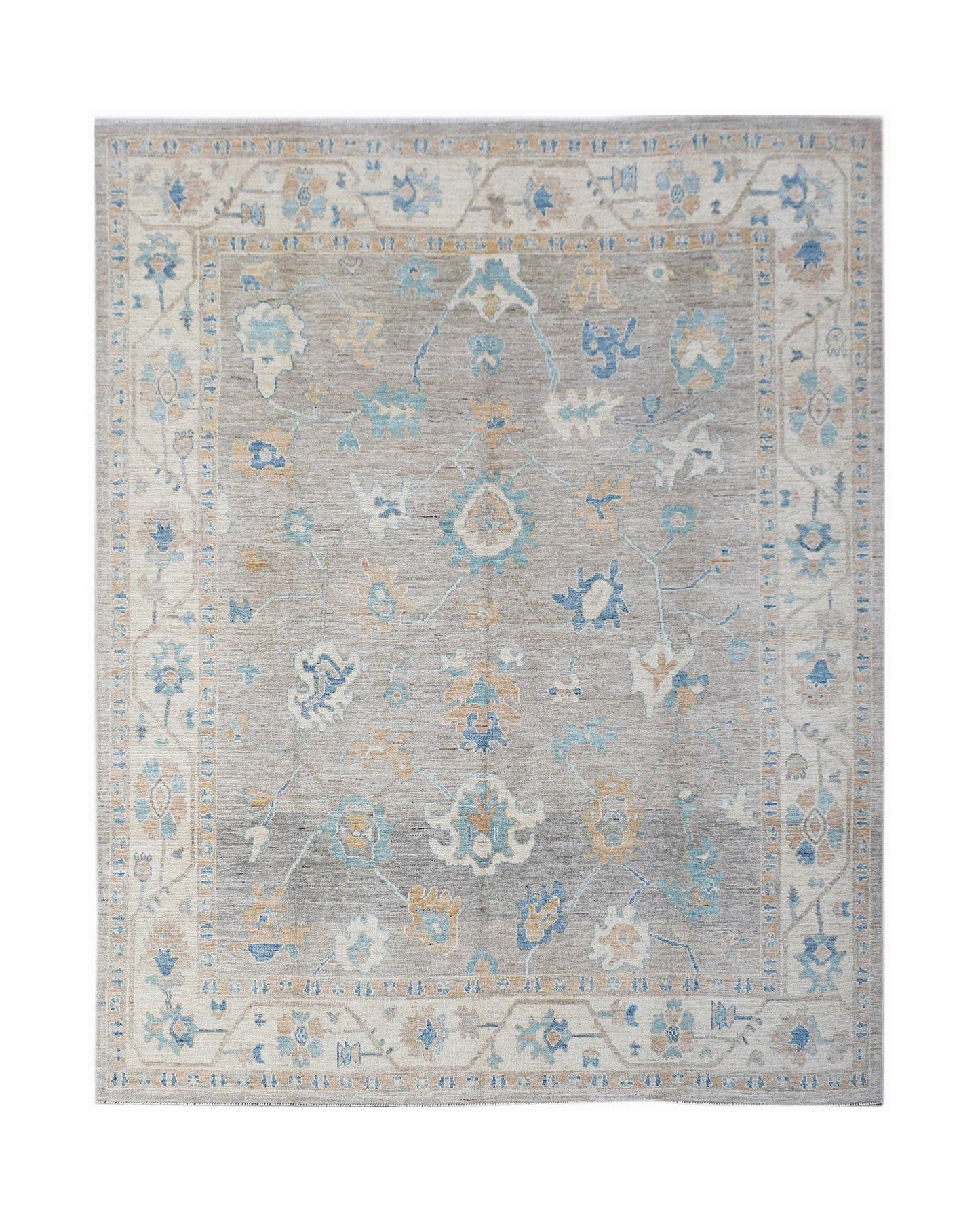 A handwoven transitional Oushak rug featuring a floral pattern in blue and tan on a grey field.