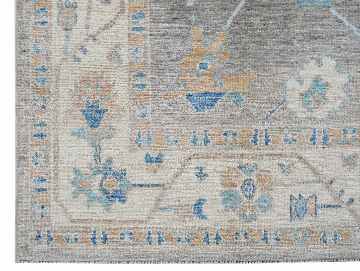 A transitional Oushak rug featuring a floral pattern in blue, beige, and grey tones.