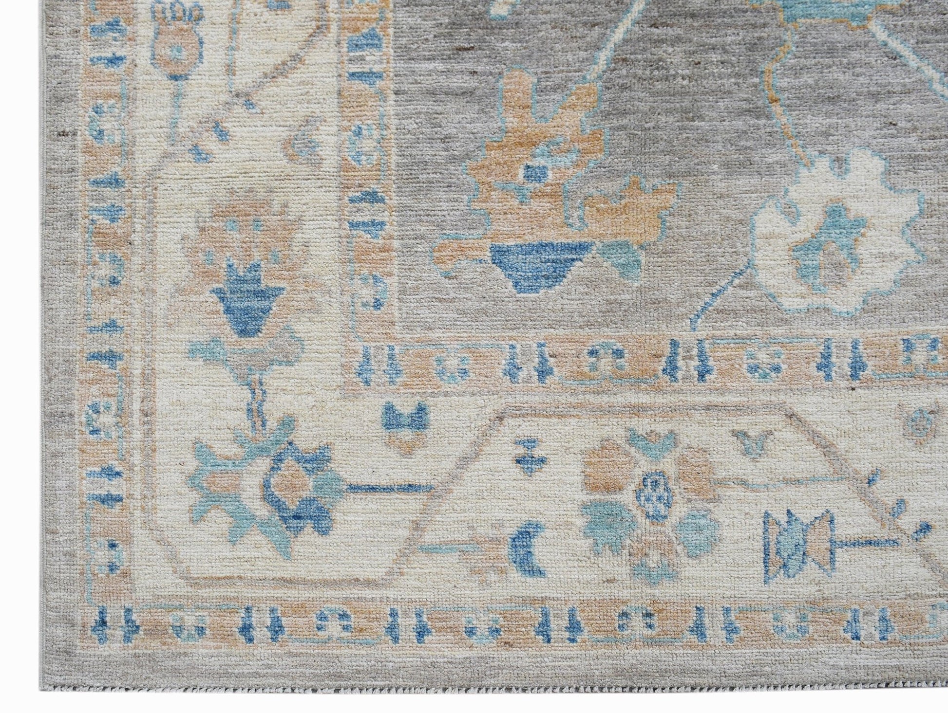 A transitional Oushak rug featuring a floral pattern in blue, beige, and grey tones.