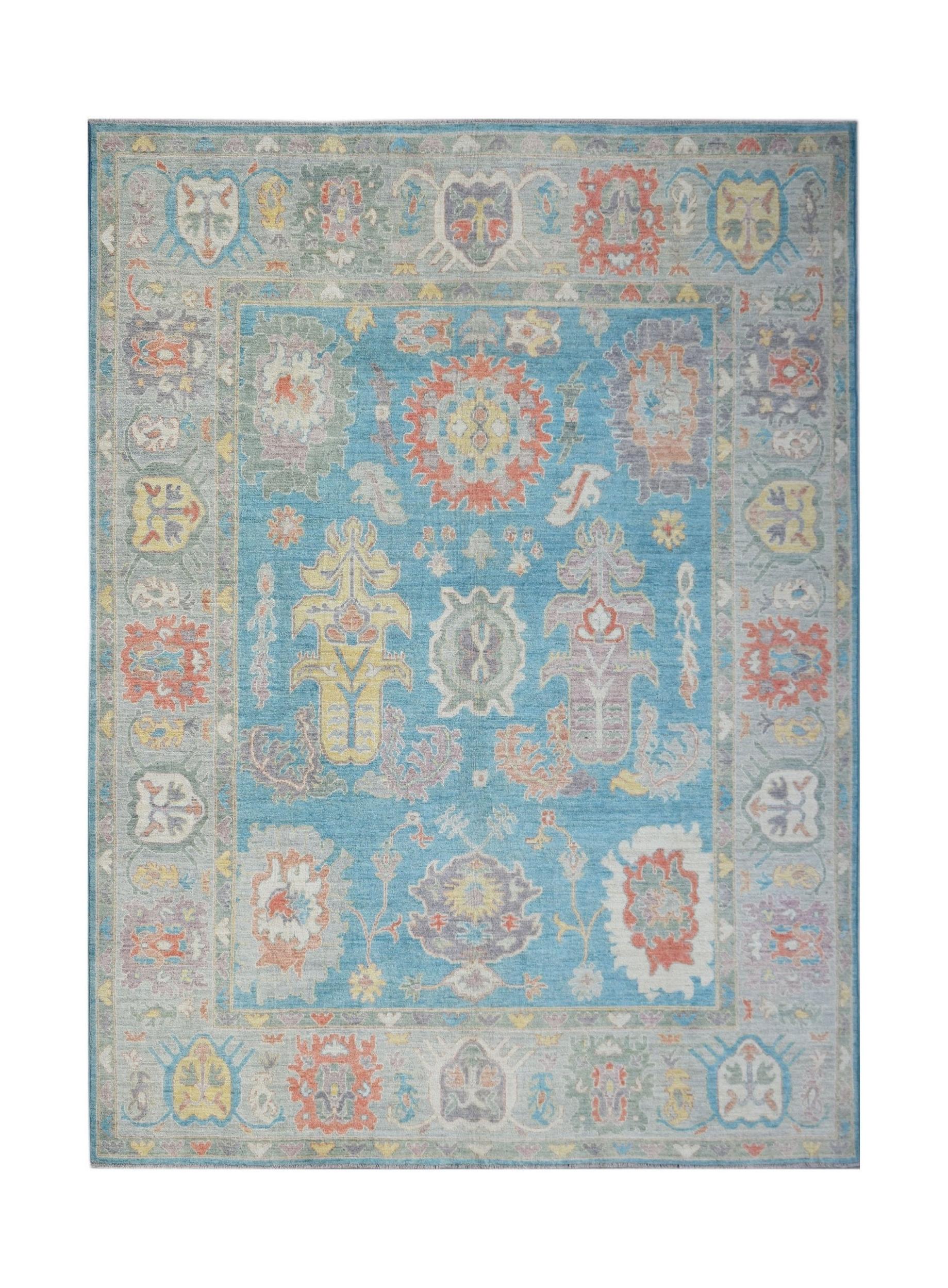A handwoven transitional Oushak rug featuring a floral pattern in blue and multi-colored tones.