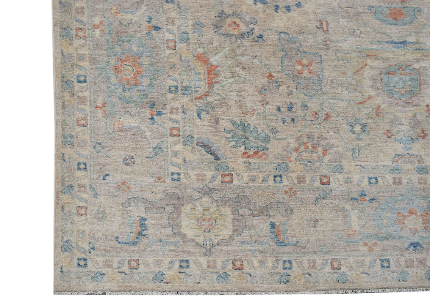 A handwoven transitional Oushak rug featuring a floral pattern in muted blue and orange tones.