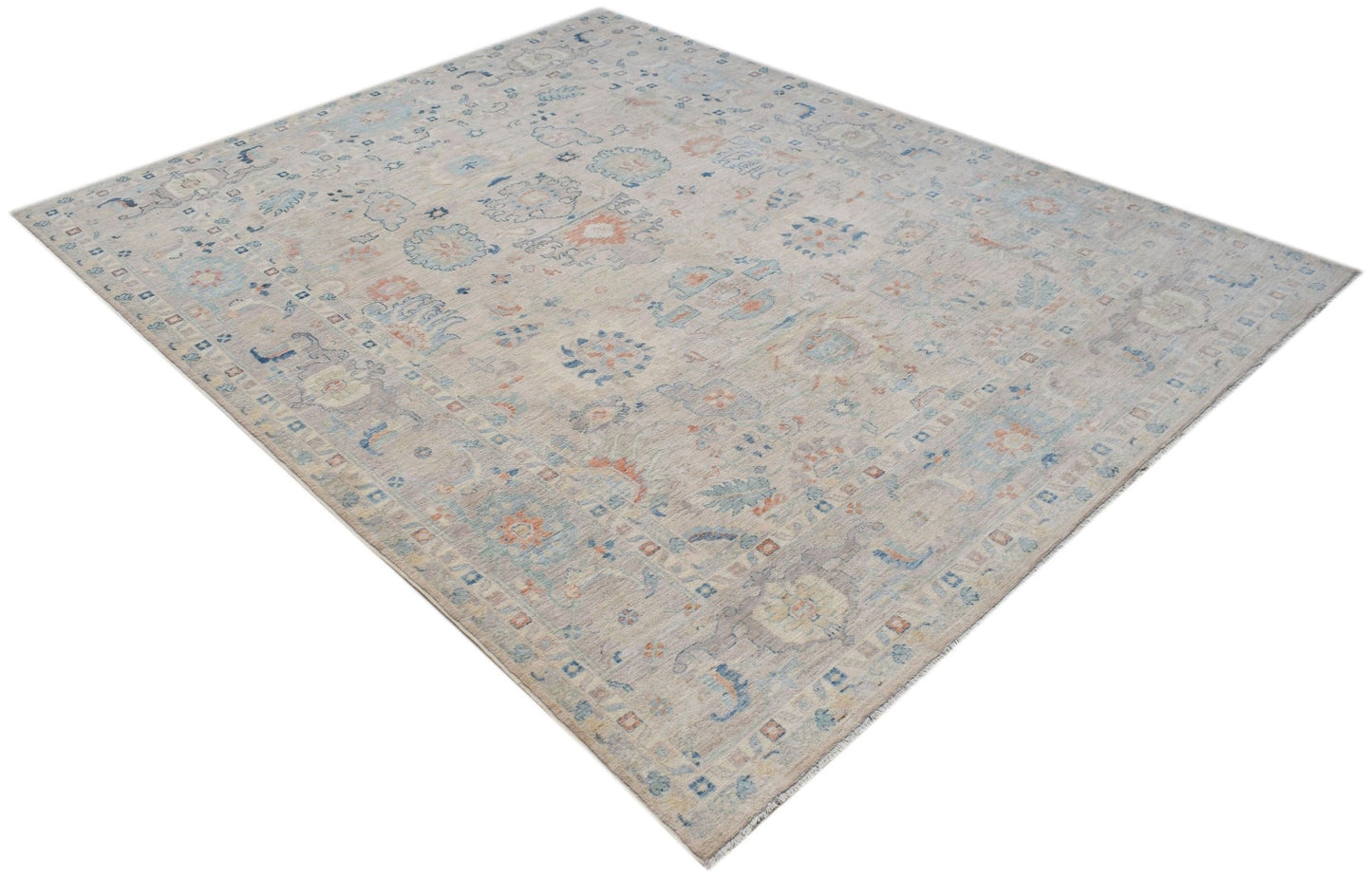 A handwoven transitional Oushak rug featuring a light floral pattern in soft blue and orange tones.