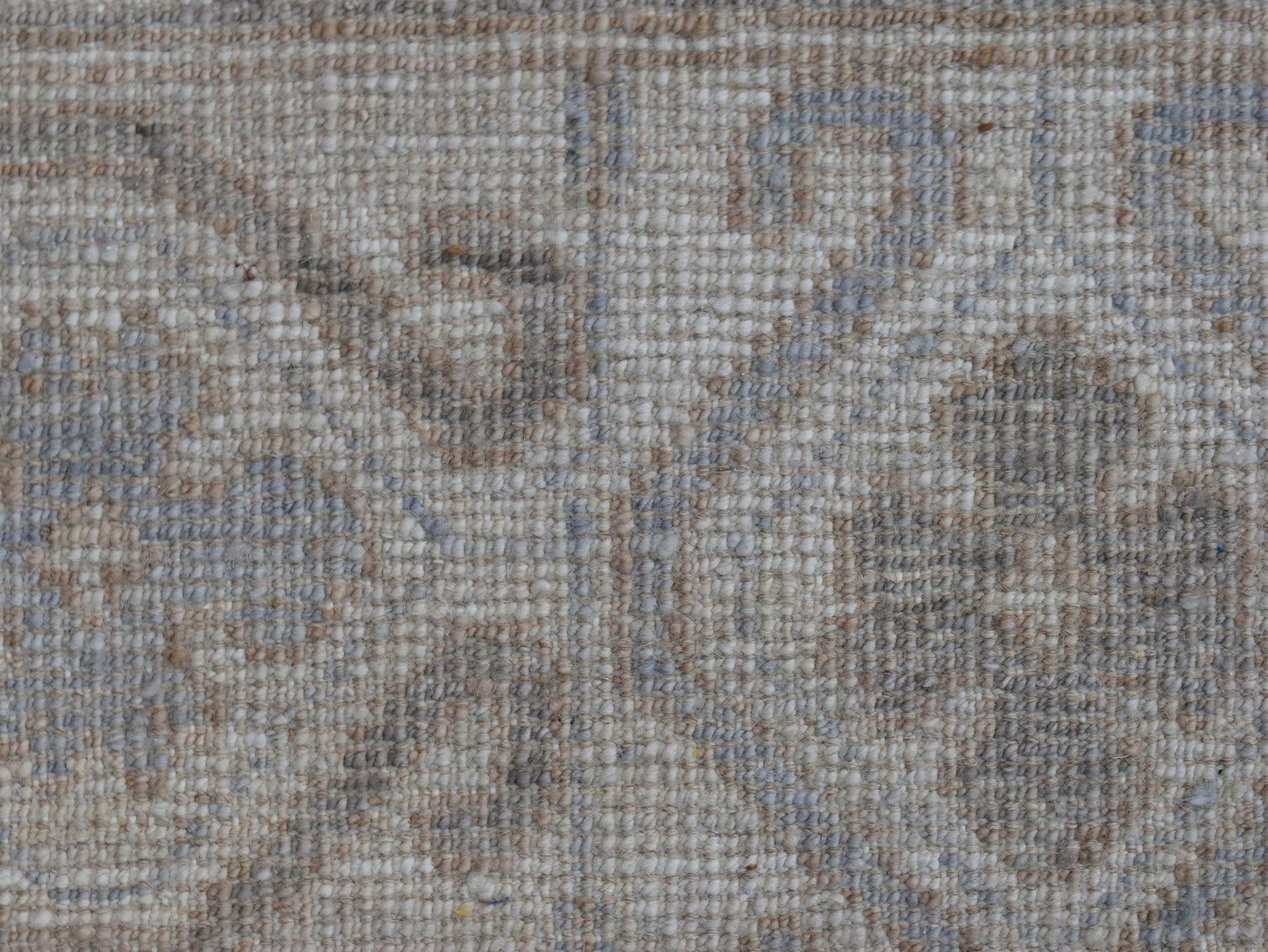A close-up view of a handwoven transitional Oushak rug featuring a soft, neutral floral pattern.