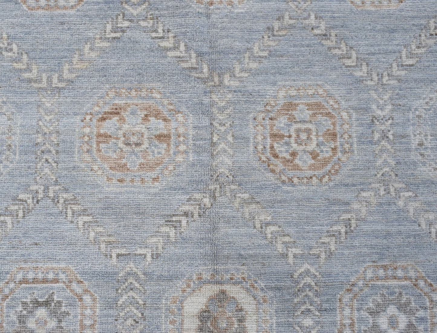 A handwoven transitional Oushak rug featuring a light blue field with geometric floral motifs.