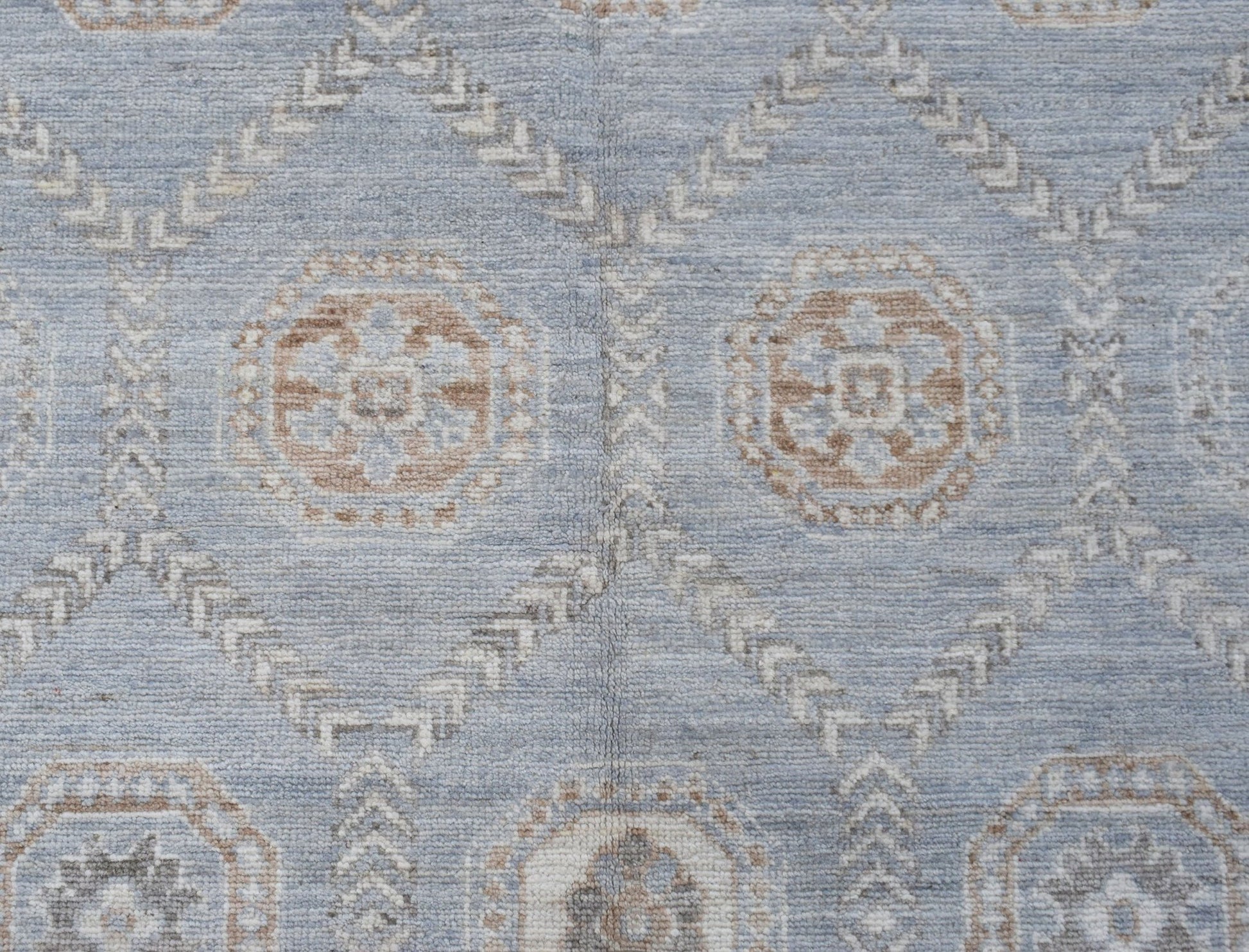 A handwoven transitional Oushak rug featuring a light blue field with geometric floral motifs.