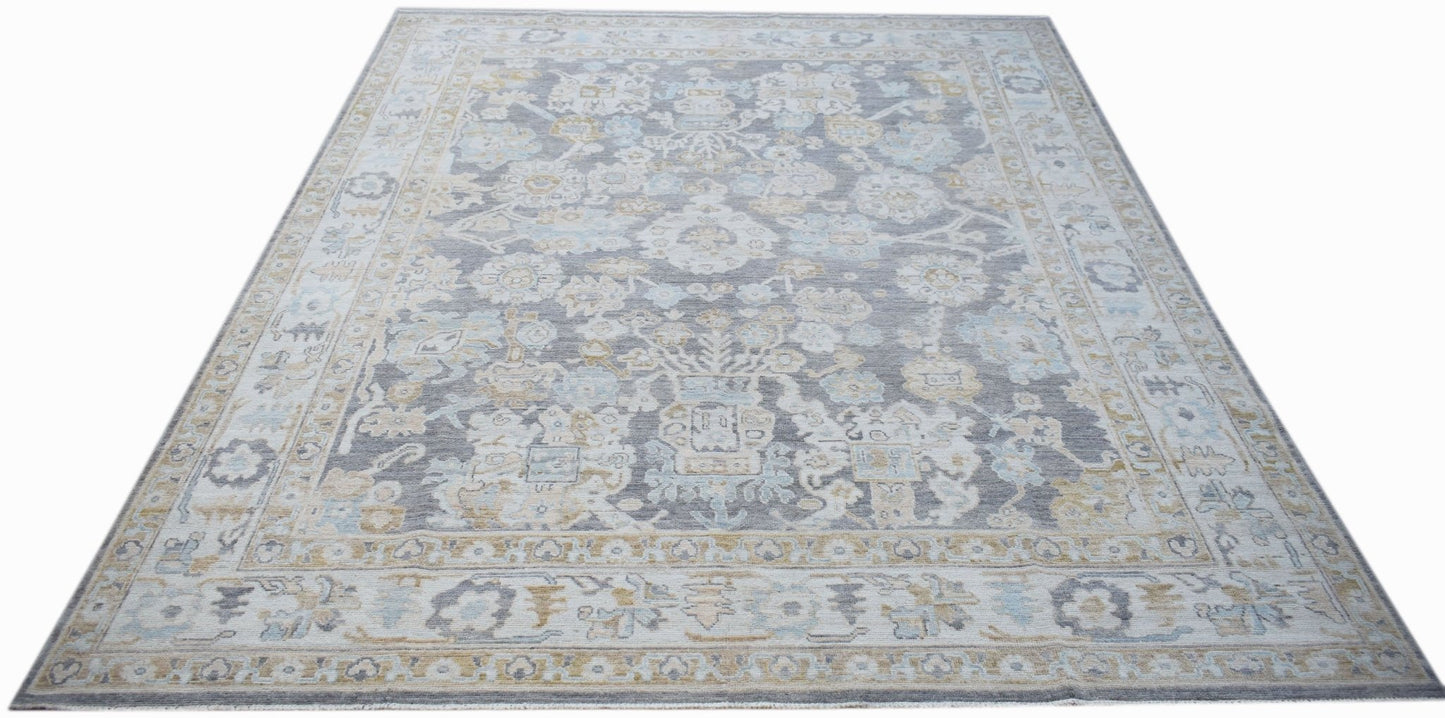 A handwoven transitional Oushak rug featuring a grey field with floral patterns in blue and gold.