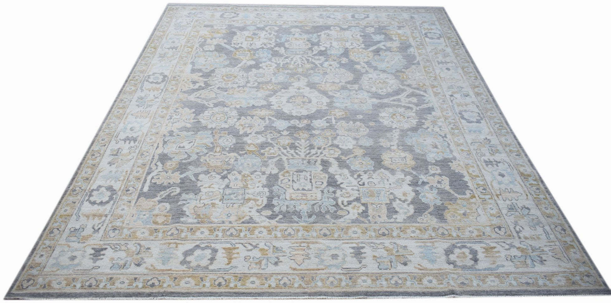 A handwoven transitional Oushak rug featuring a grey field with floral patterns in blue and gold.
