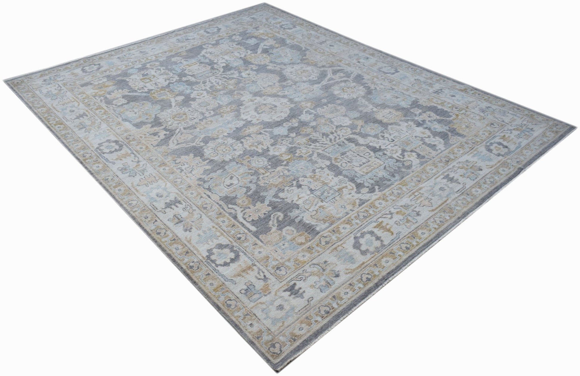 A handwoven transitional Oushak rug featuring a floral pattern in grey, blue, and beige tones.