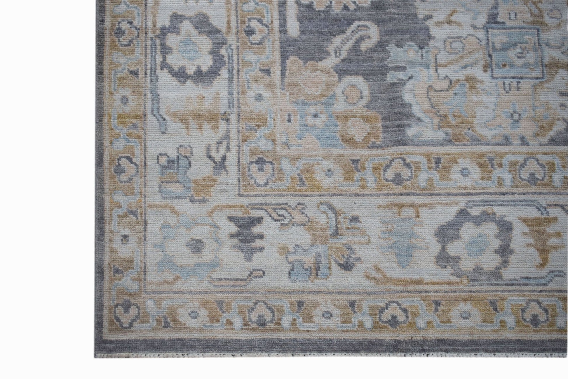 A transitional Oushak rug featuring a floral pattern in grey, blue, and tan tones.
