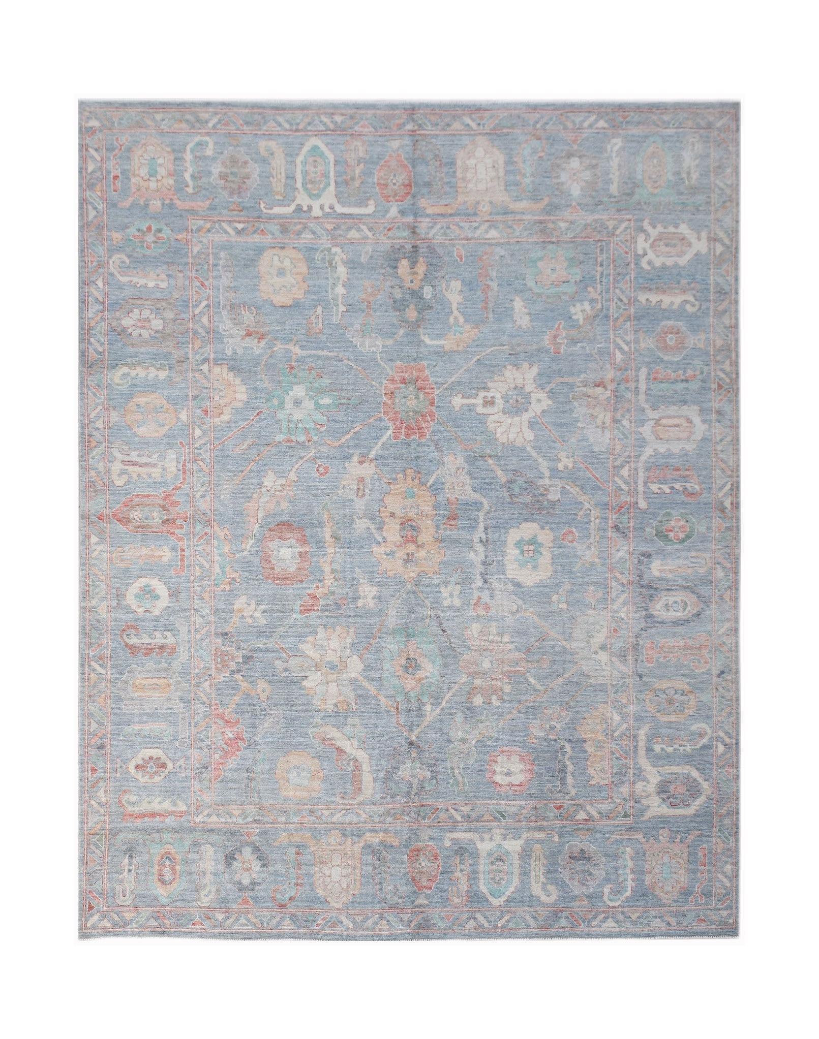 A handwoven transitional Oushak rug featuring a floral pattern in soft blue and muted tones.