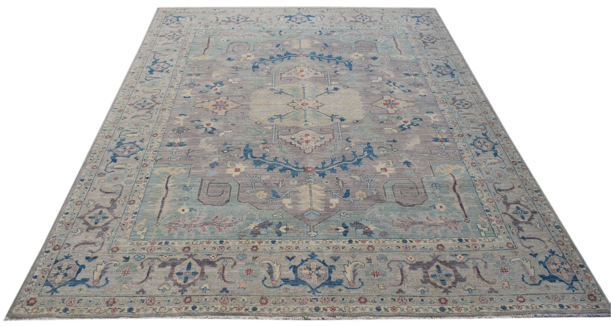 A handwoven transitional Oushak rug featuring a floral pattern in muted blue and grey tones.