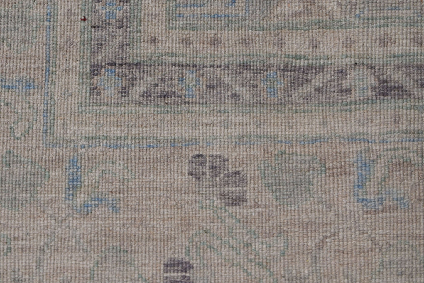 A close-up of a handwoven transitional Oushak rug featuring a muted floral pattern in wool.