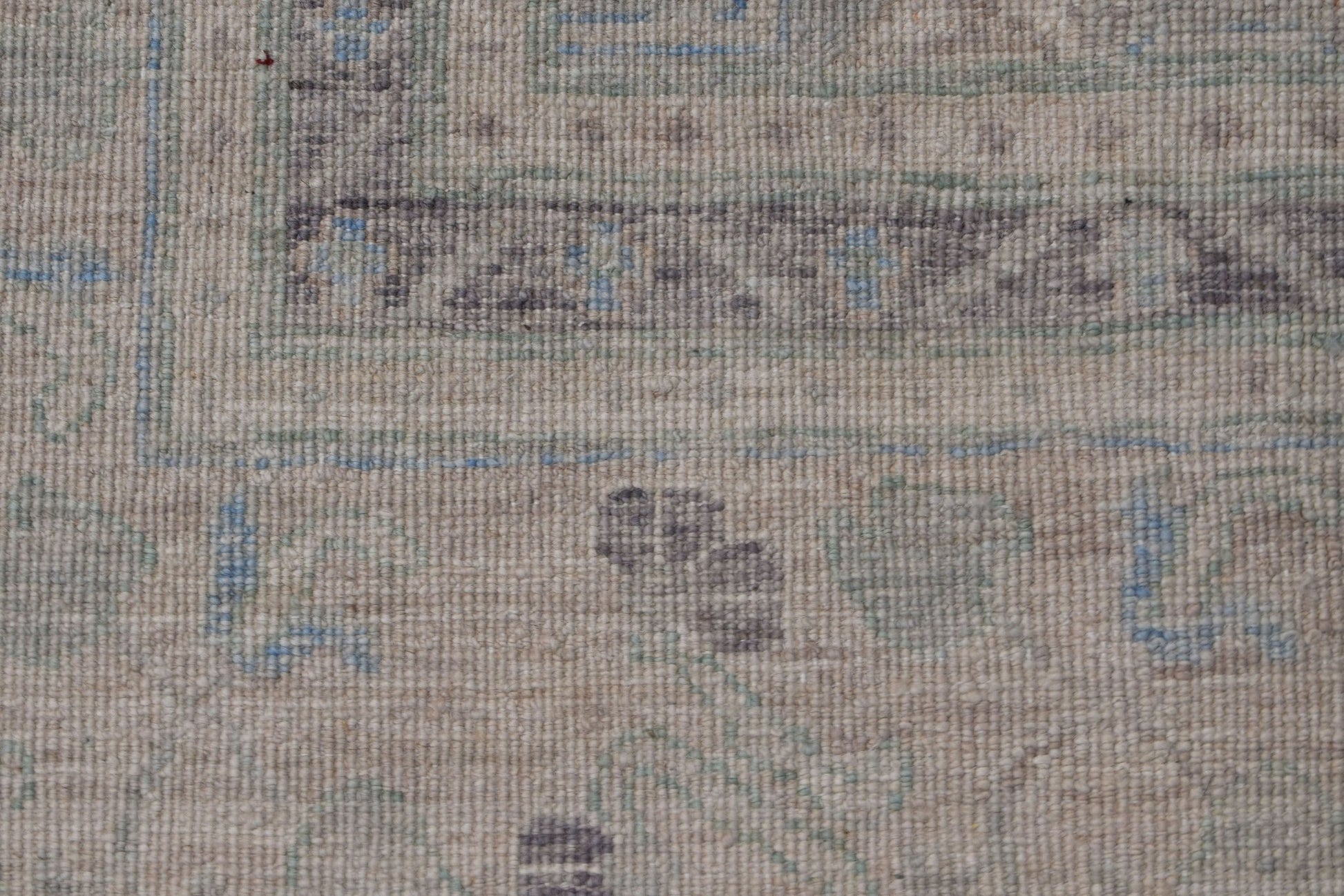 A close-up of a handwoven transitional Oushak rug featuring a muted floral pattern in wool.