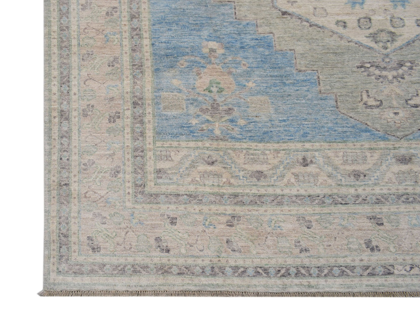 A handwoven transitional Oushak rug featuring a blue and beige floral pattern with a fringed edge.