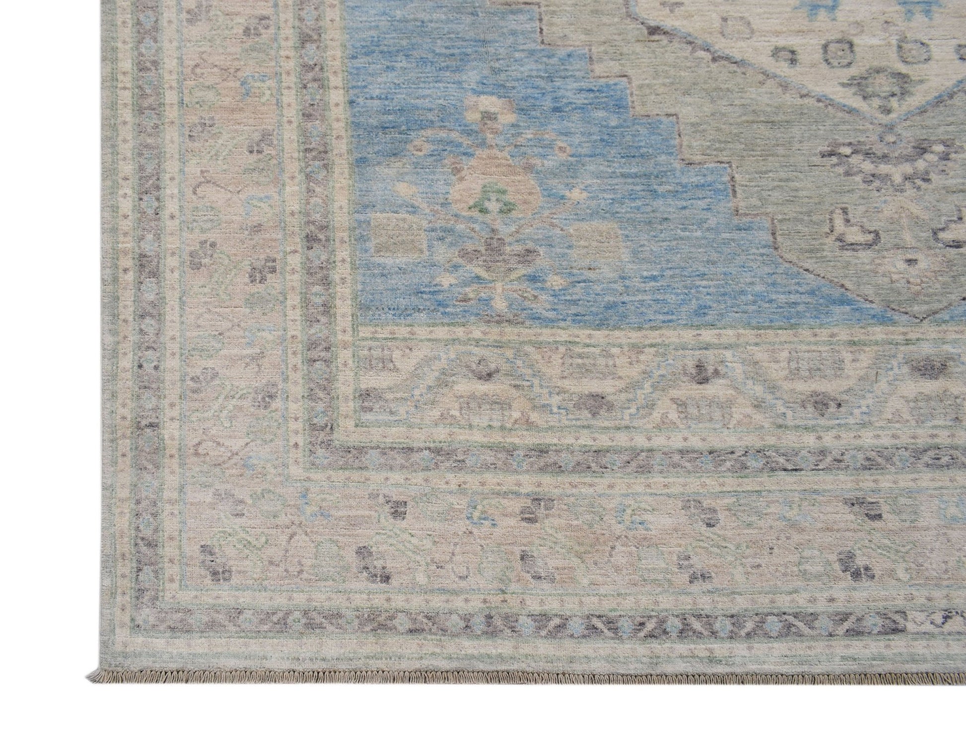 A handwoven transitional Oushak rug featuring a blue and beige floral pattern with a fringed edge.