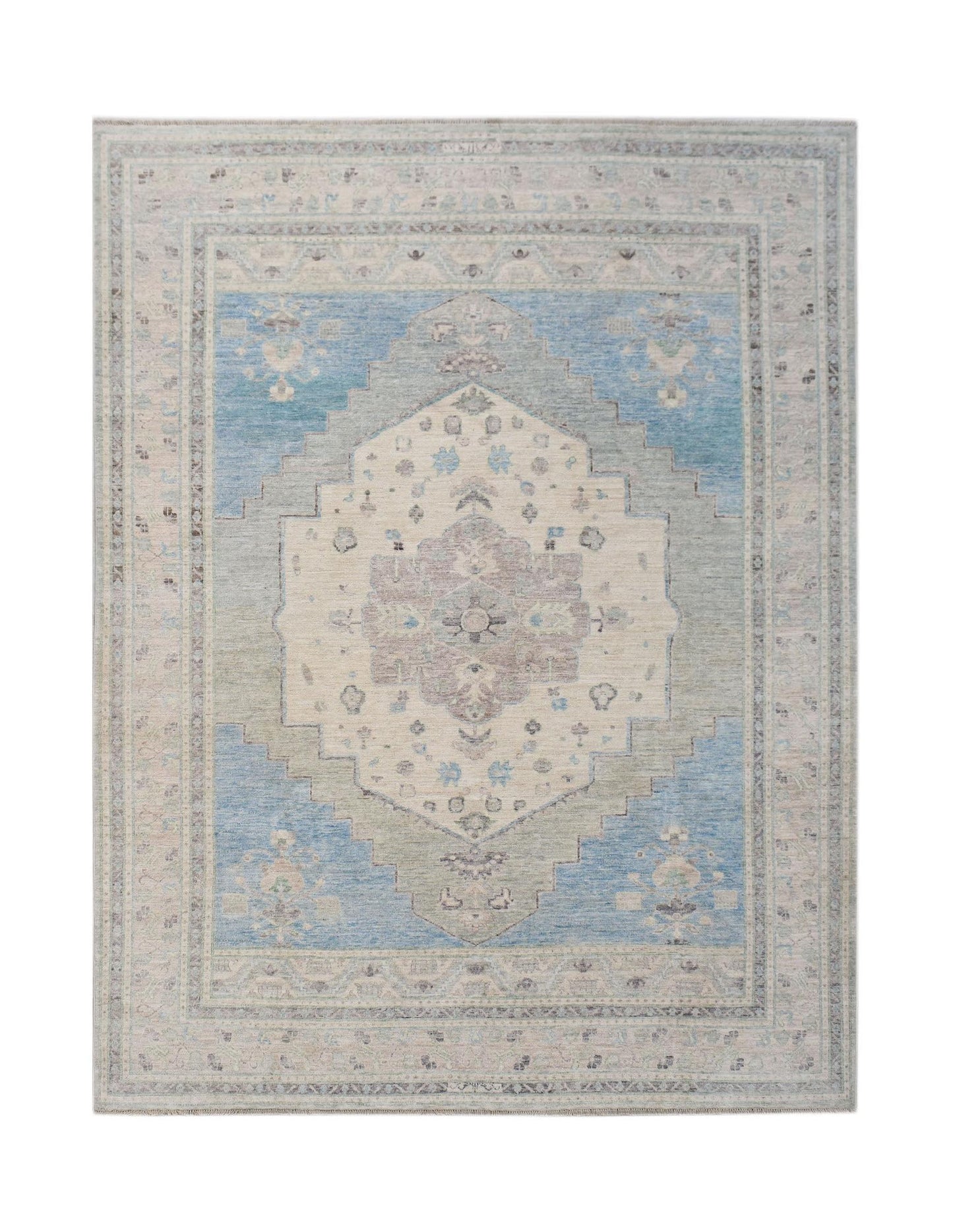 A handwoven transitional Oushak rug featuring a central floral medallion in blue and beige tones.