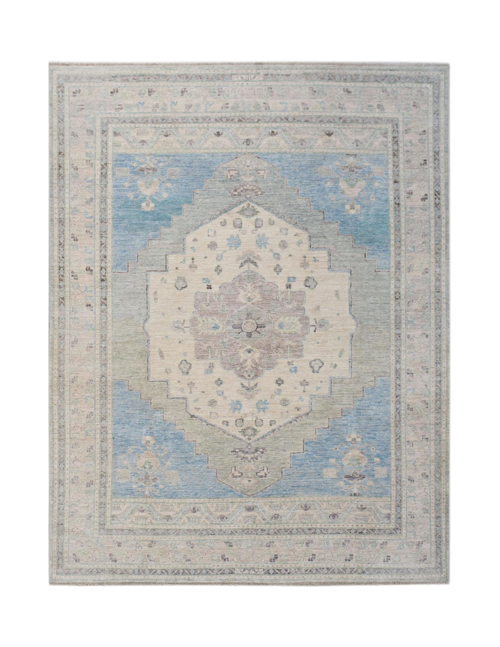 A handwoven transitional Oushak rug featuring a central floral medallion in blue and beige tones.