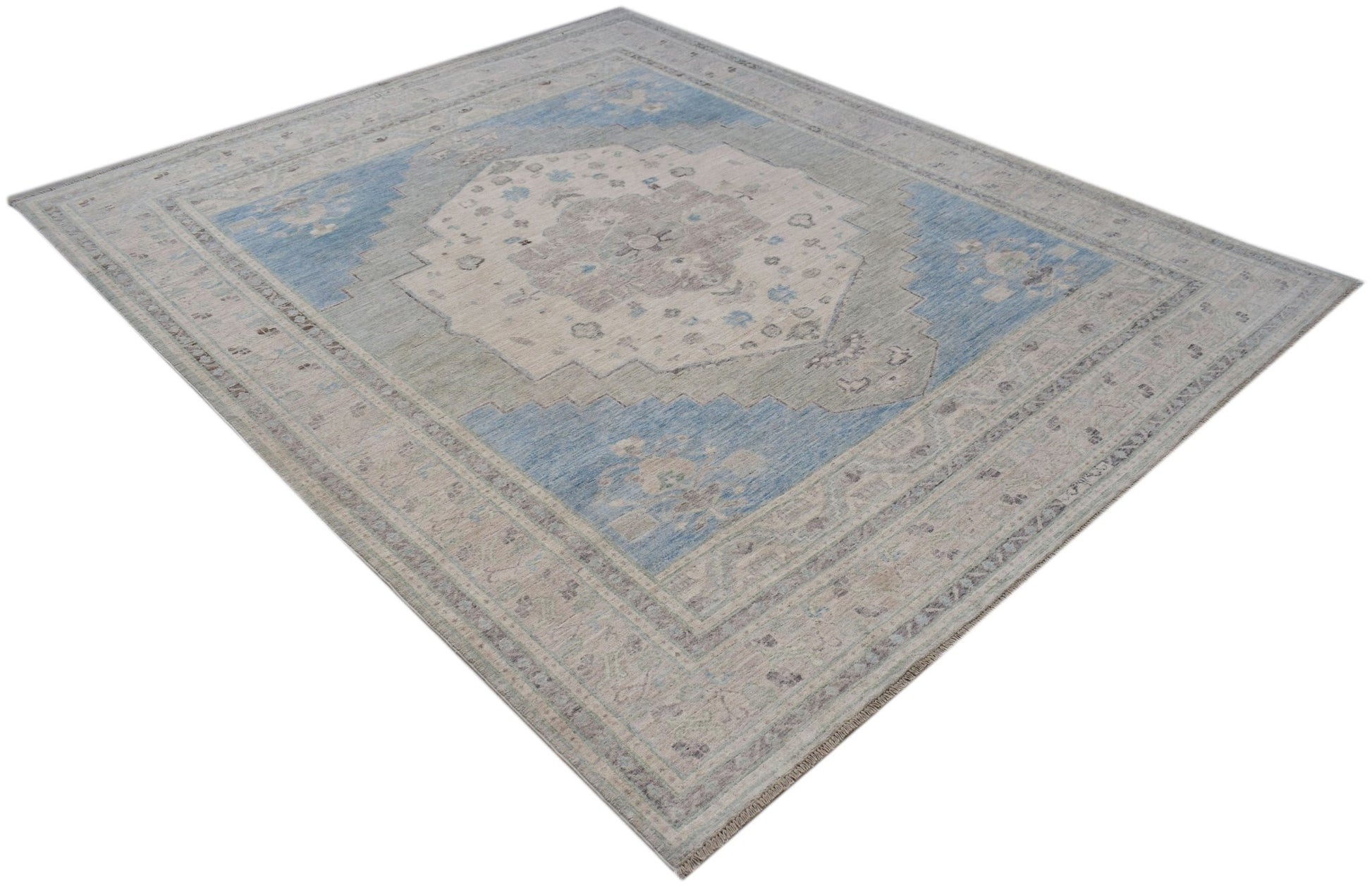 A handwoven transitional Oushak rug featuring a floral pattern in shades of blue, grey, and cream.