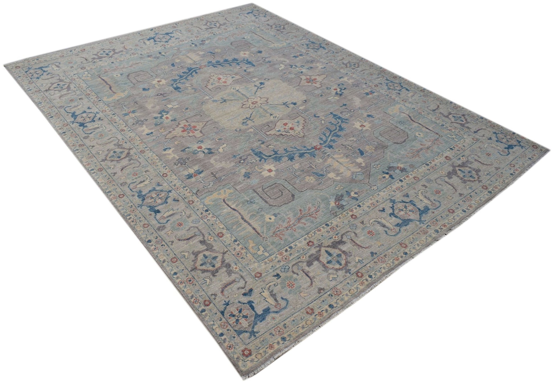 A handwoven transitional Oushak rug featuring a floral pattern in muted blue and grey tones.