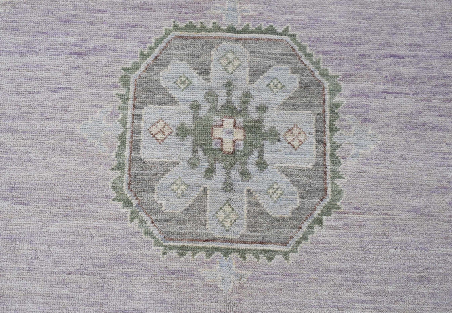A handwoven transitional Oushak rug featuring a central floral medallion in soft lavender and grey.