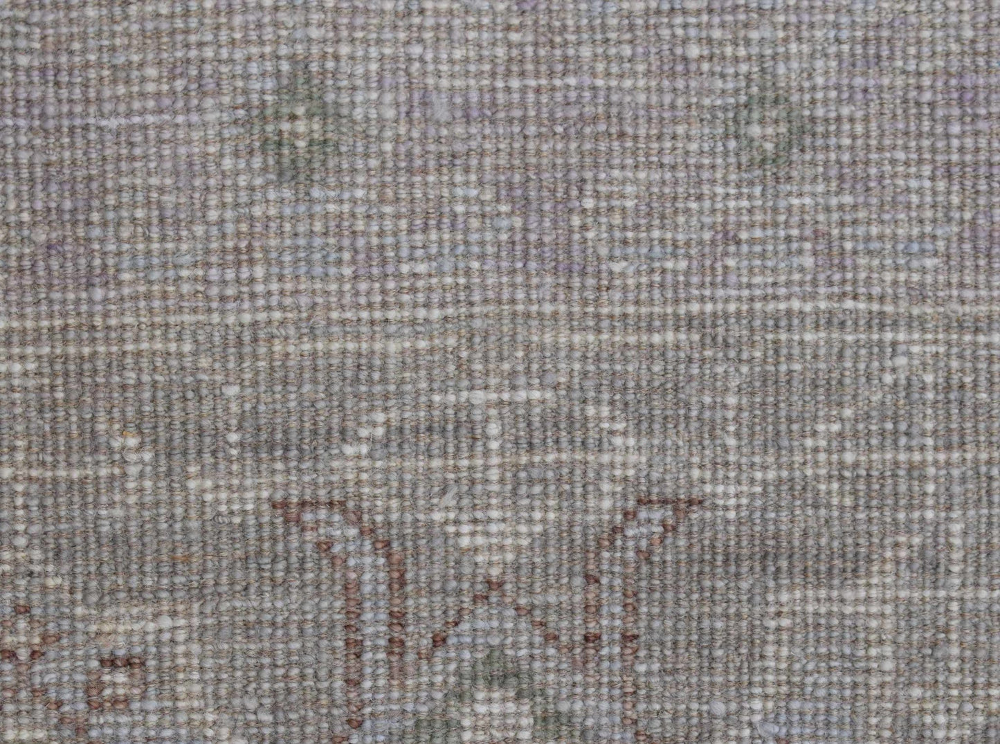 A close-up of a handwoven transitional Oushak rug featuring a subtle floral pattern in neutral tones.