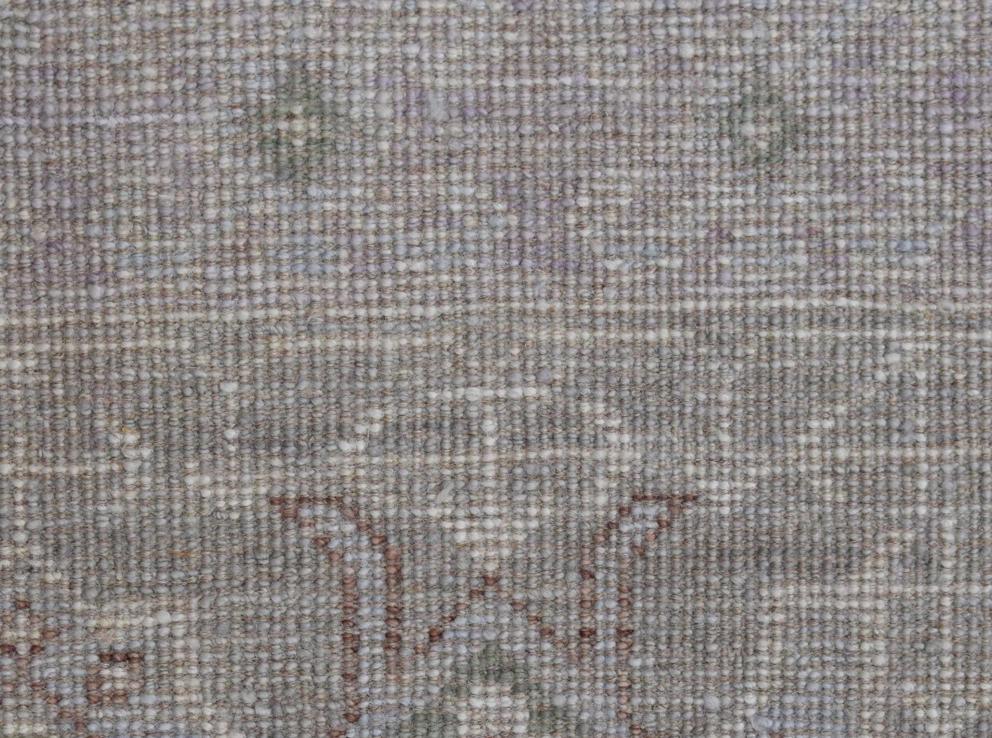 A close-up of a handwoven transitional Oushak rug featuring a subtle floral pattern in neutral tones.
