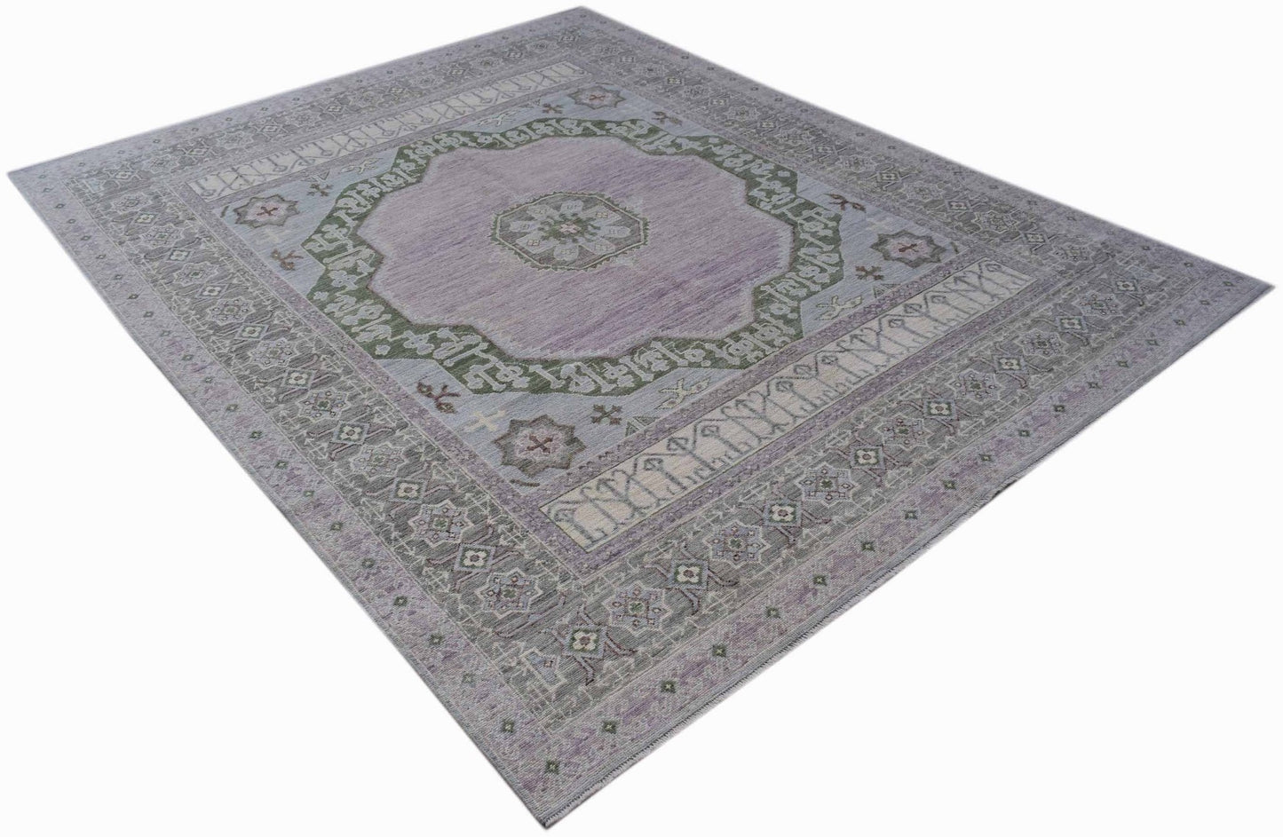 A handwoven transitional Oushak rug featuring a lavender center with green and grey floral motifs.