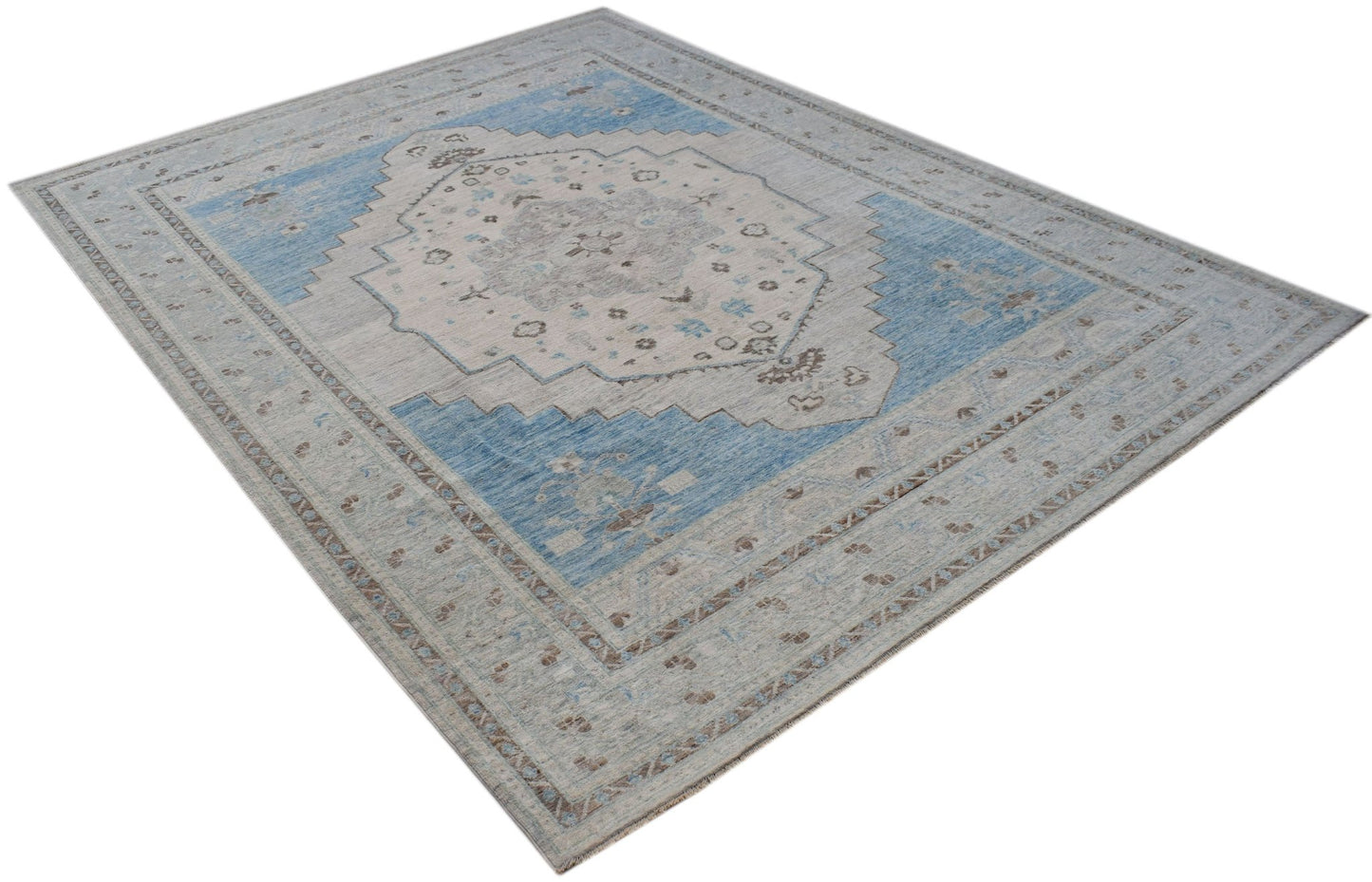A handwoven transitional Oushak rug featuring a blue and beige floral medallion pattern.