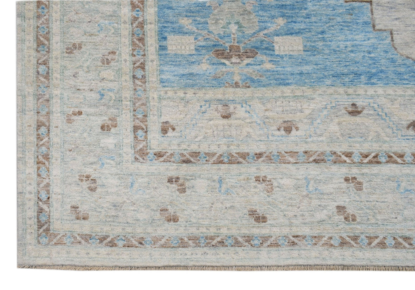 A handwoven transitional Oushak rug featuring a blue central field with floral patterns.