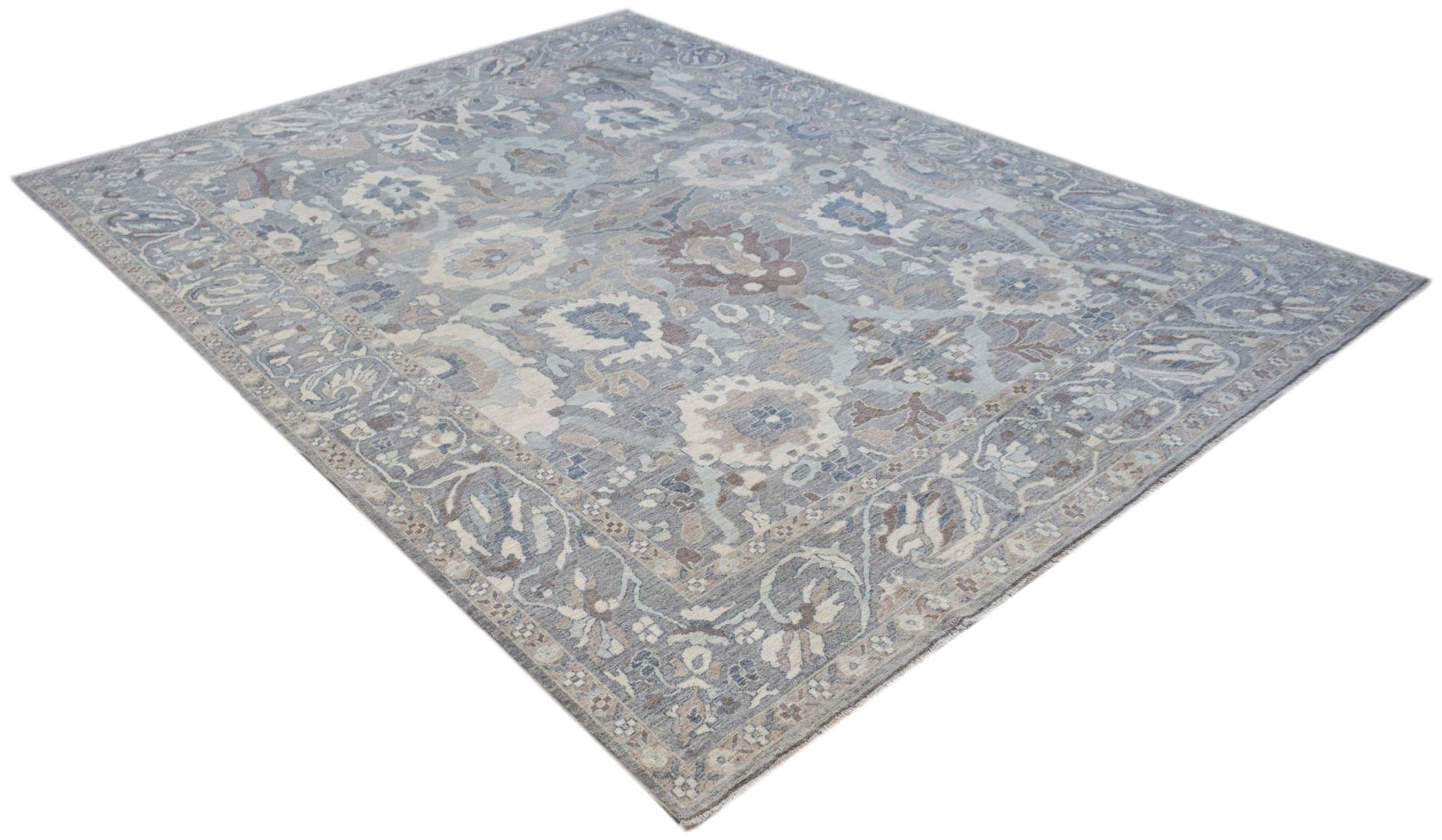 A handwoven transitional Oushak rug featuring a floral pattern in shades of blue and grey.