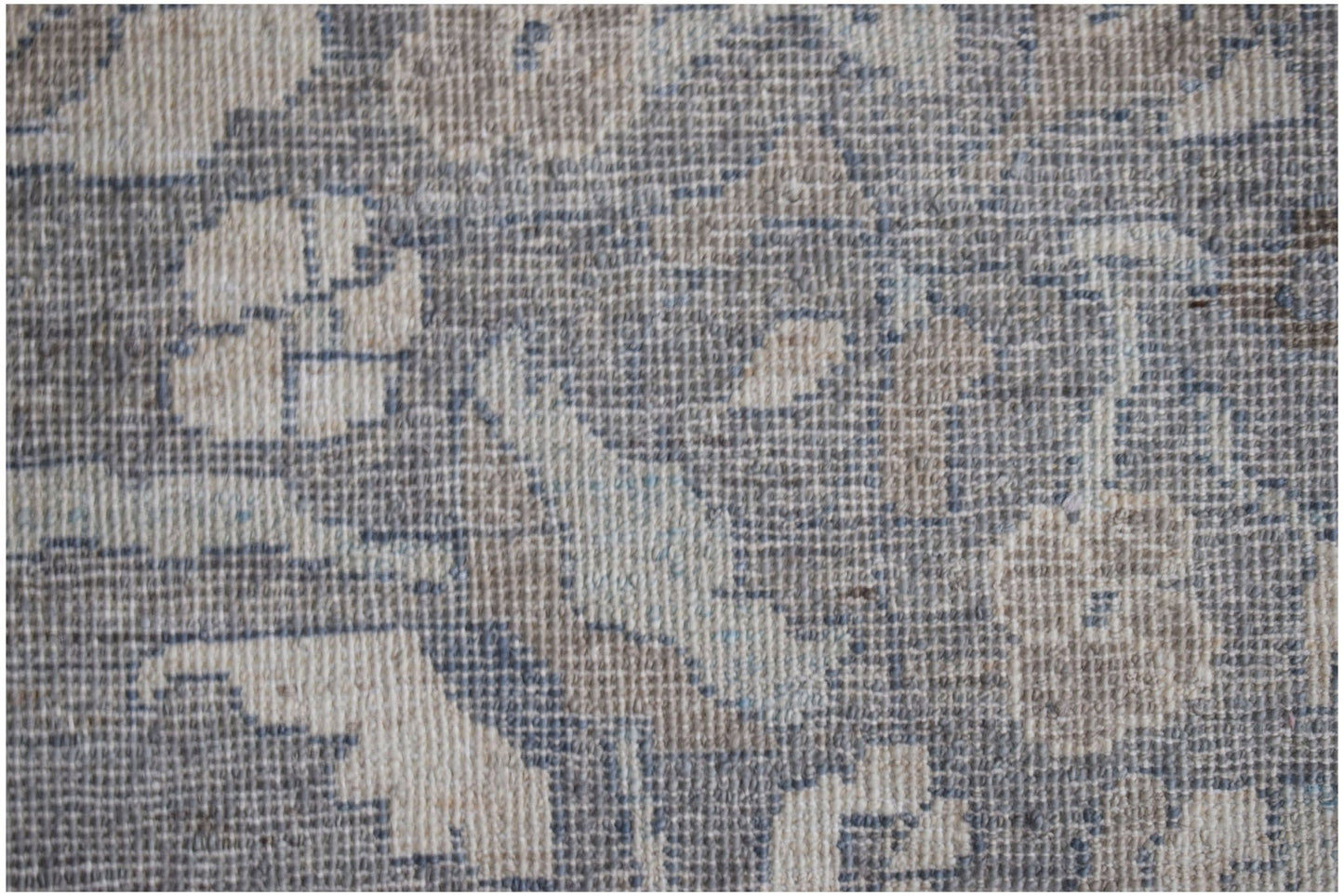 A close-up of a handwoven transitional Oushak rug featuring a floral pattern in blue and beige.