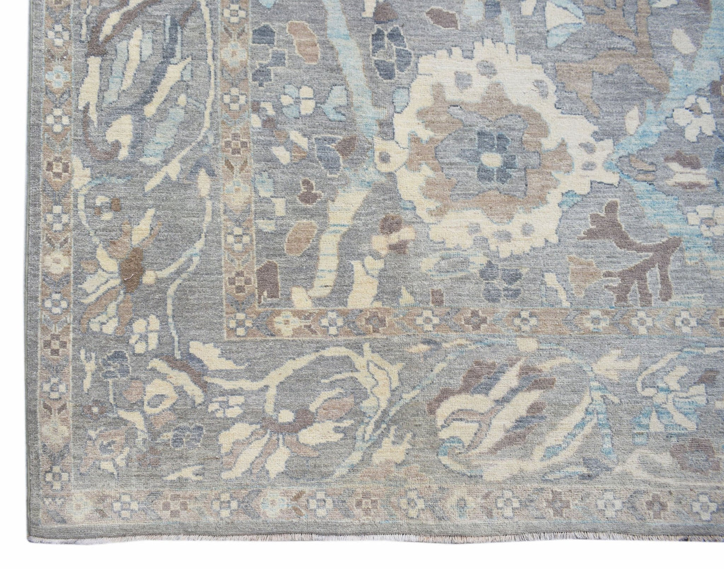 A handwoven transitional Oushak rug featuring a floral pattern in shades of grey, blue, and beige.