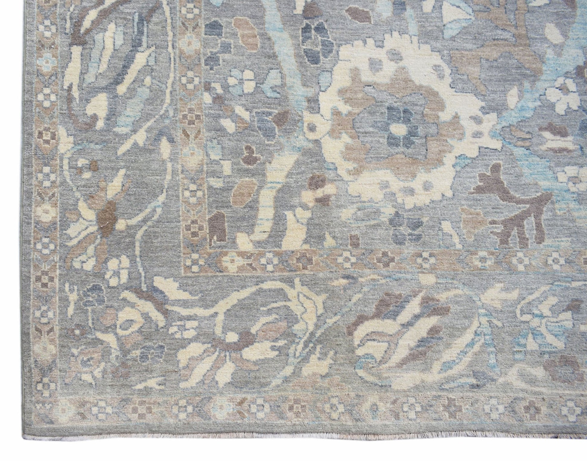 A handwoven transitional Oushak rug featuring a floral pattern in shades of grey, blue, and beige.