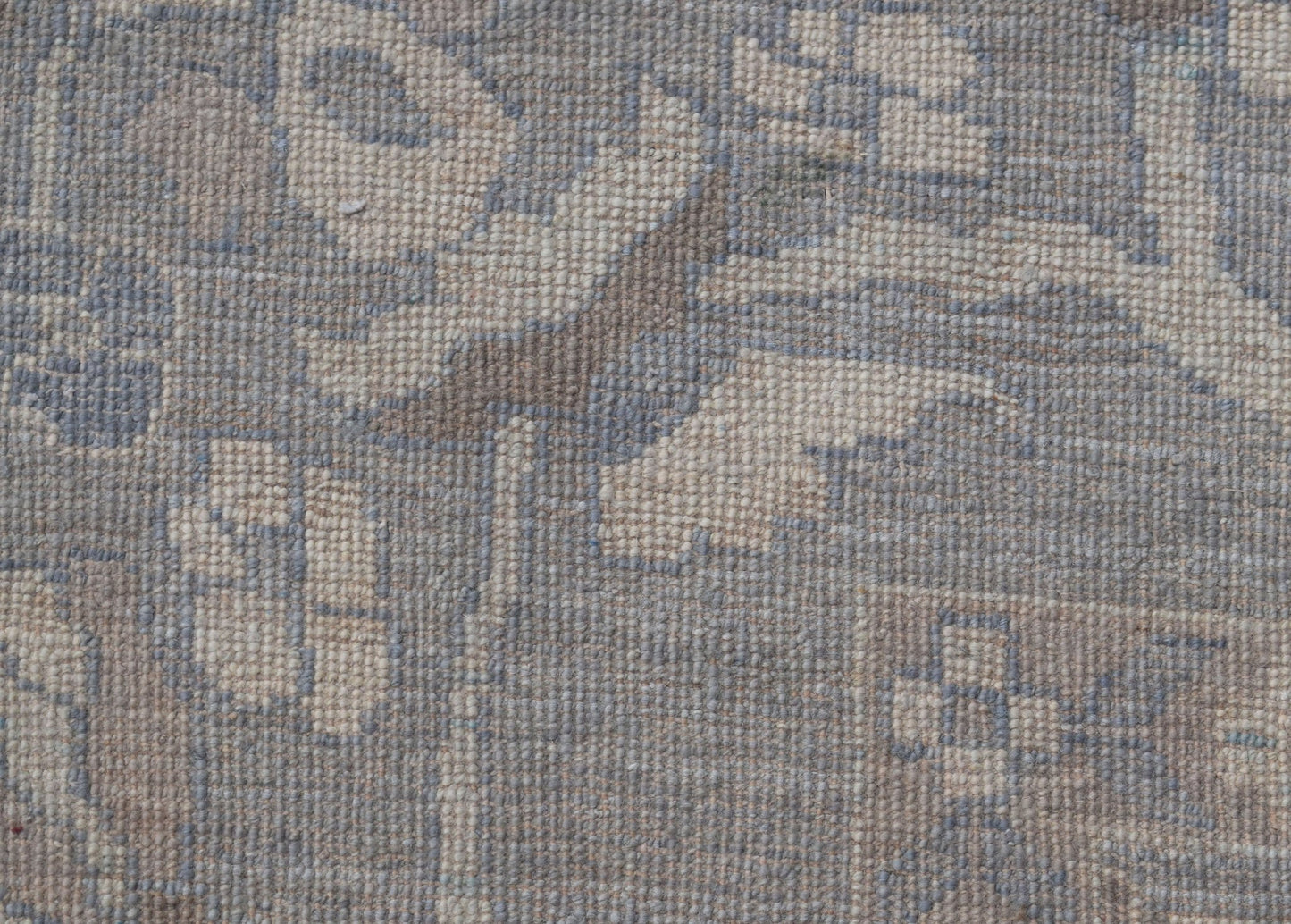 A handwoven transitional Oushak rug featuring a floral pattern in muted blue and beige tones.