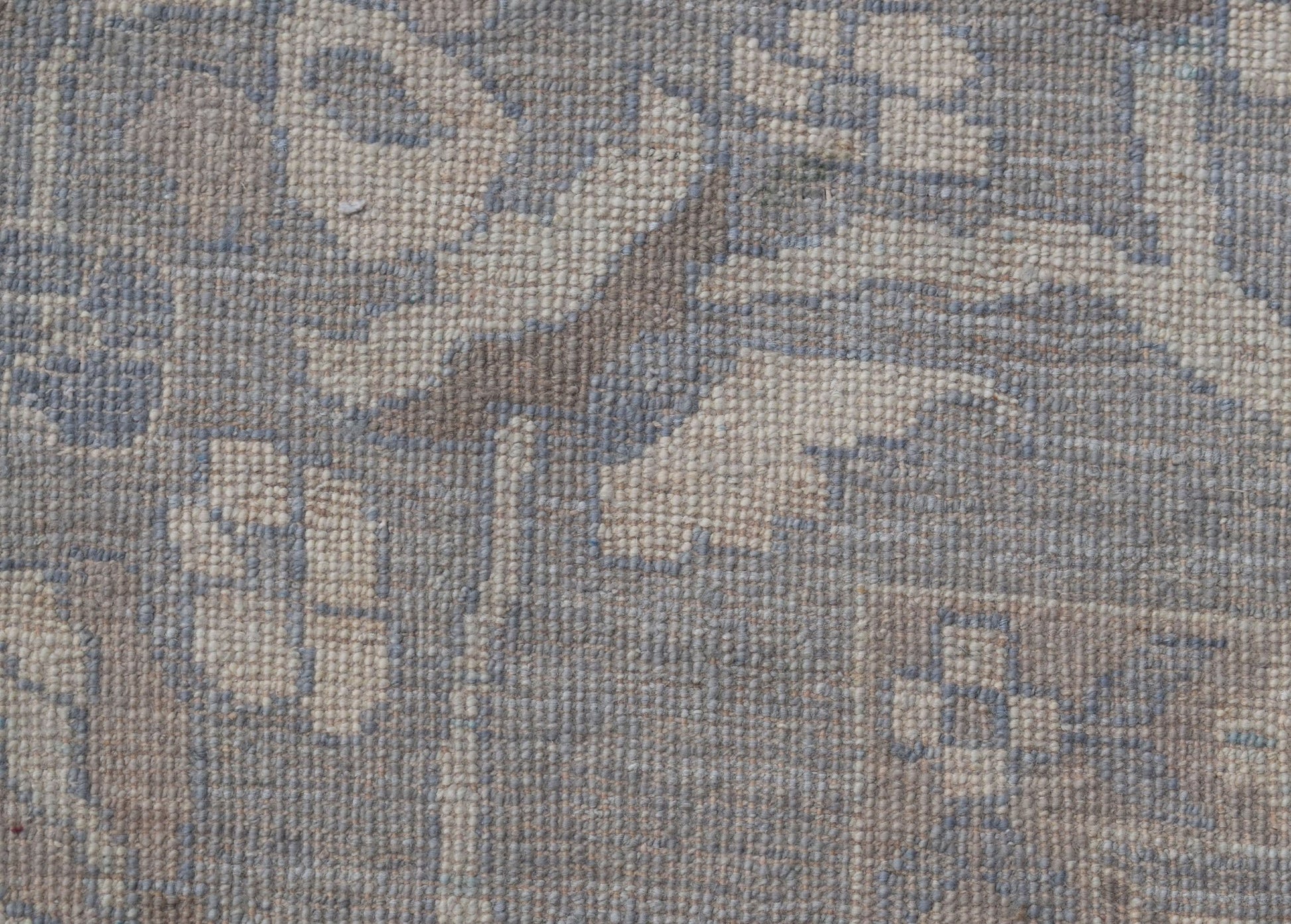 A handwoven transitional Oushak rug featuring a floral pattern in muted blue and beige tones.