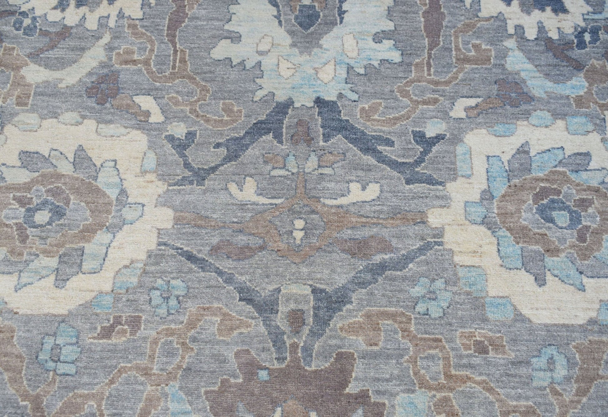 A handwoven transitional Oushak rug featuring a floral pattern in shades of blue, grey, and cream.