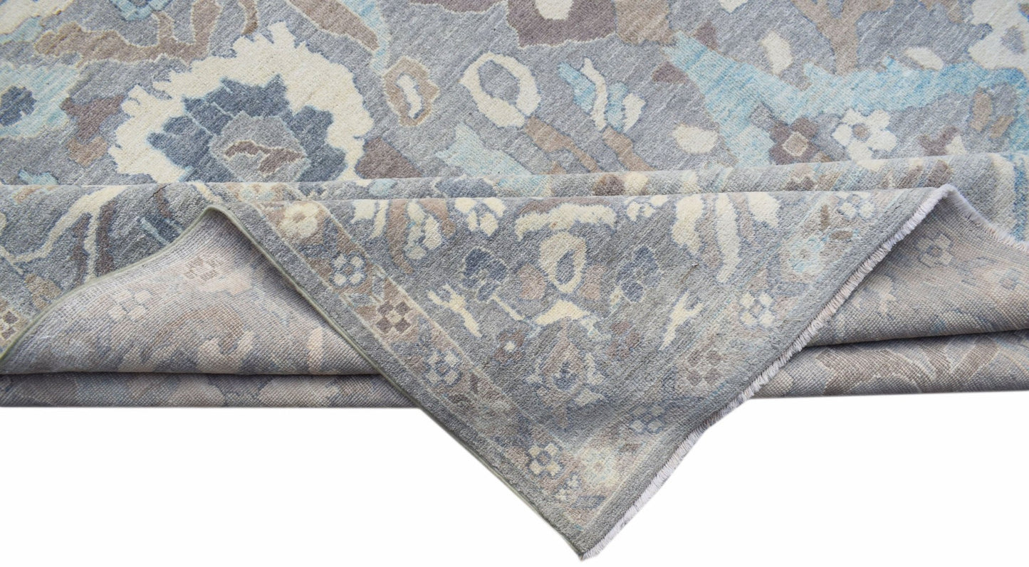 A handwoven transitional Oushak rug featuring a floral pattern in shades of blue, grey, and beige.