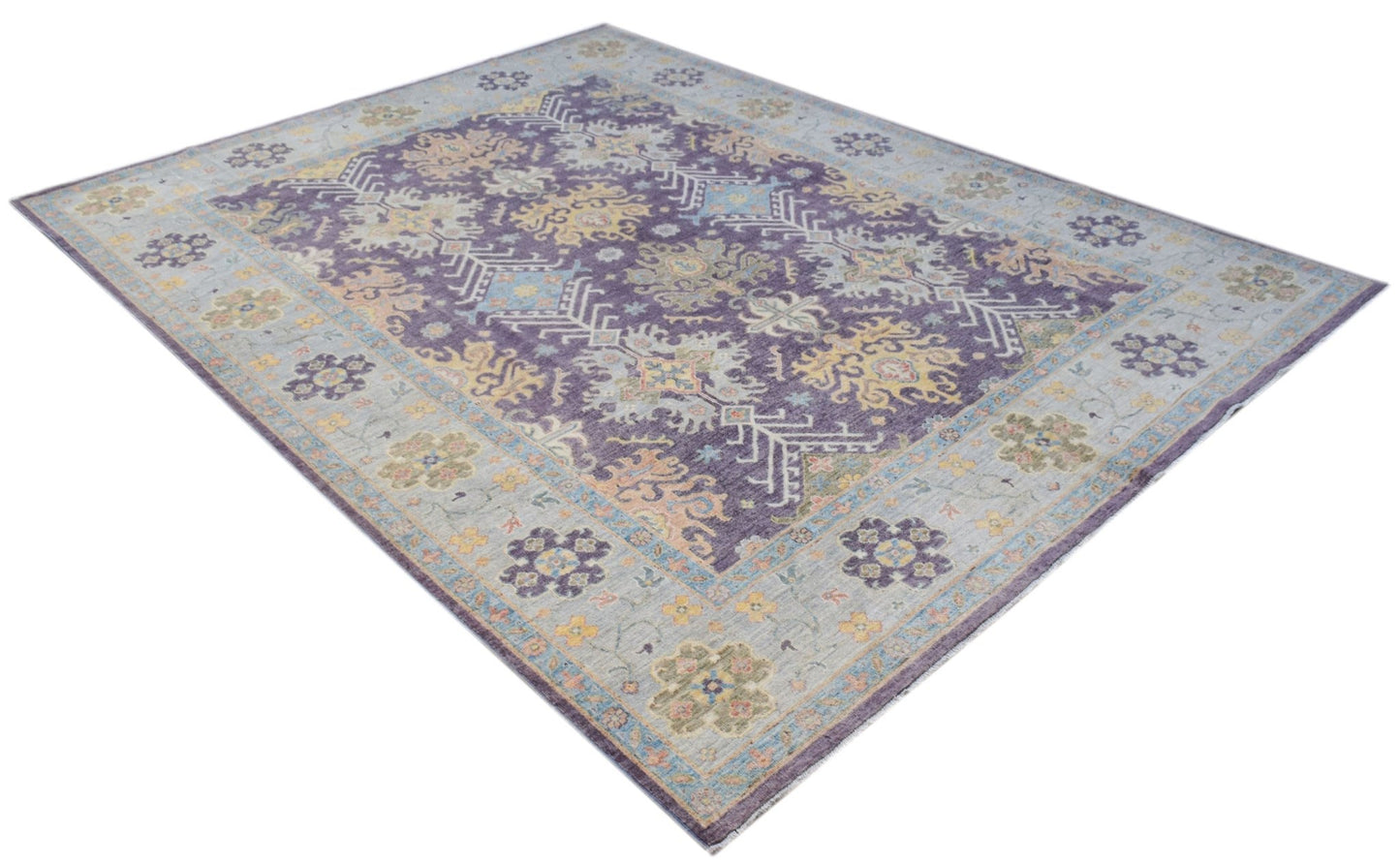 A handwoven transitional Oushak rug featuring a floral pattern in purple, blue, and yellow tones.