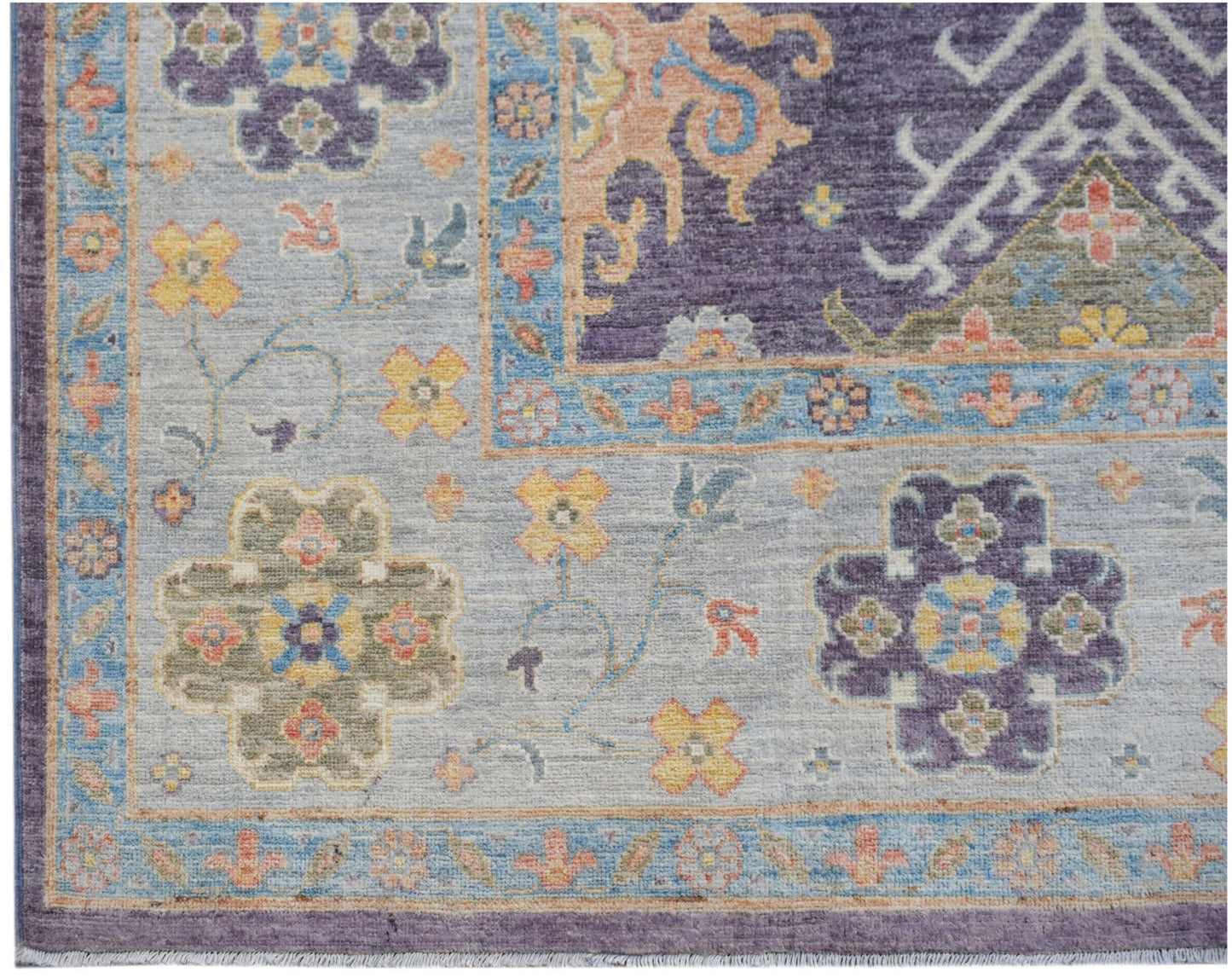 A handwoven transitional Oushak rug featuring a floral pattern in purple, blue, and soft orange.