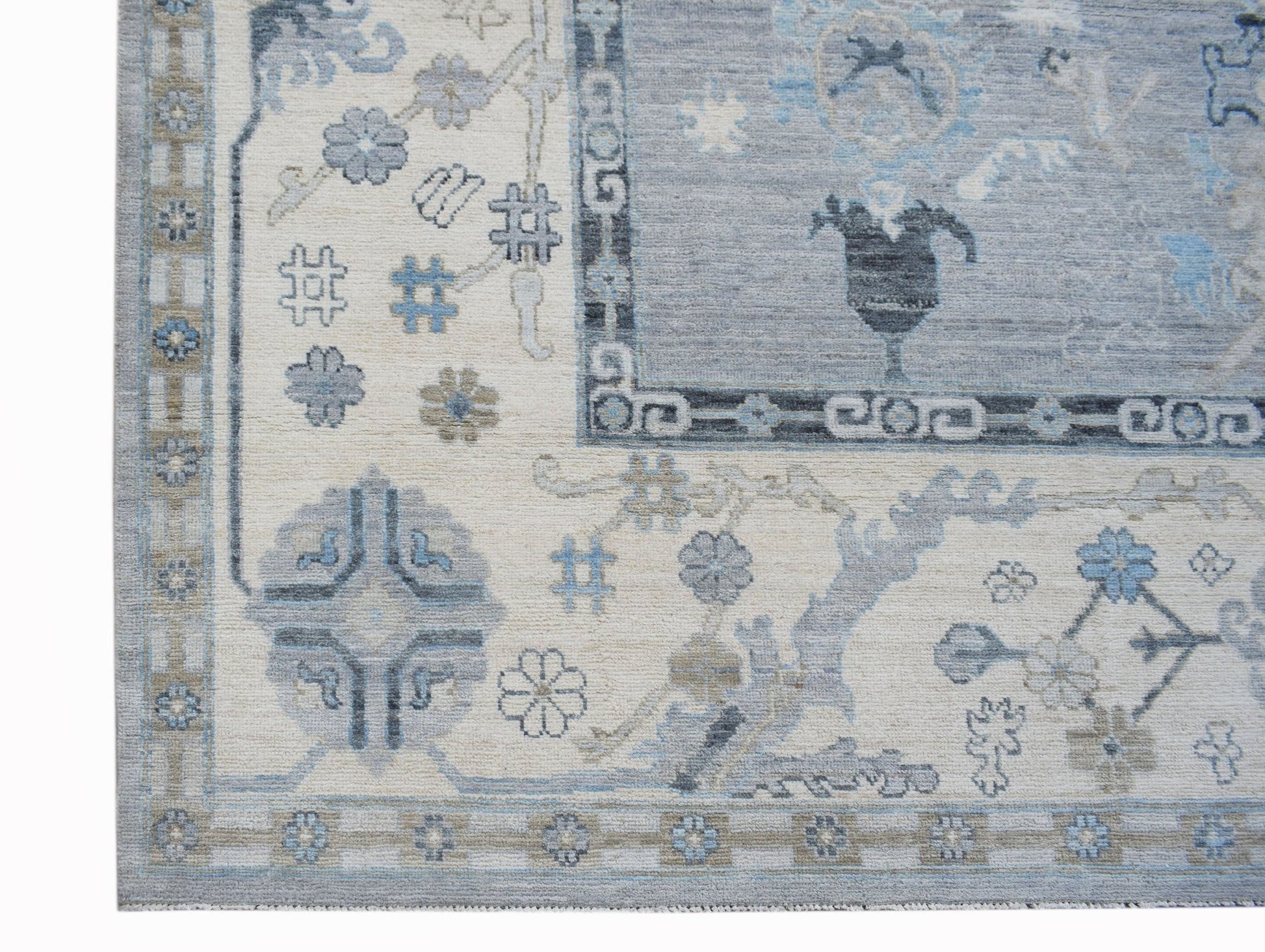 A handwoven transitional Oushak rug featuring a floral pattern in shades of blue and cream.